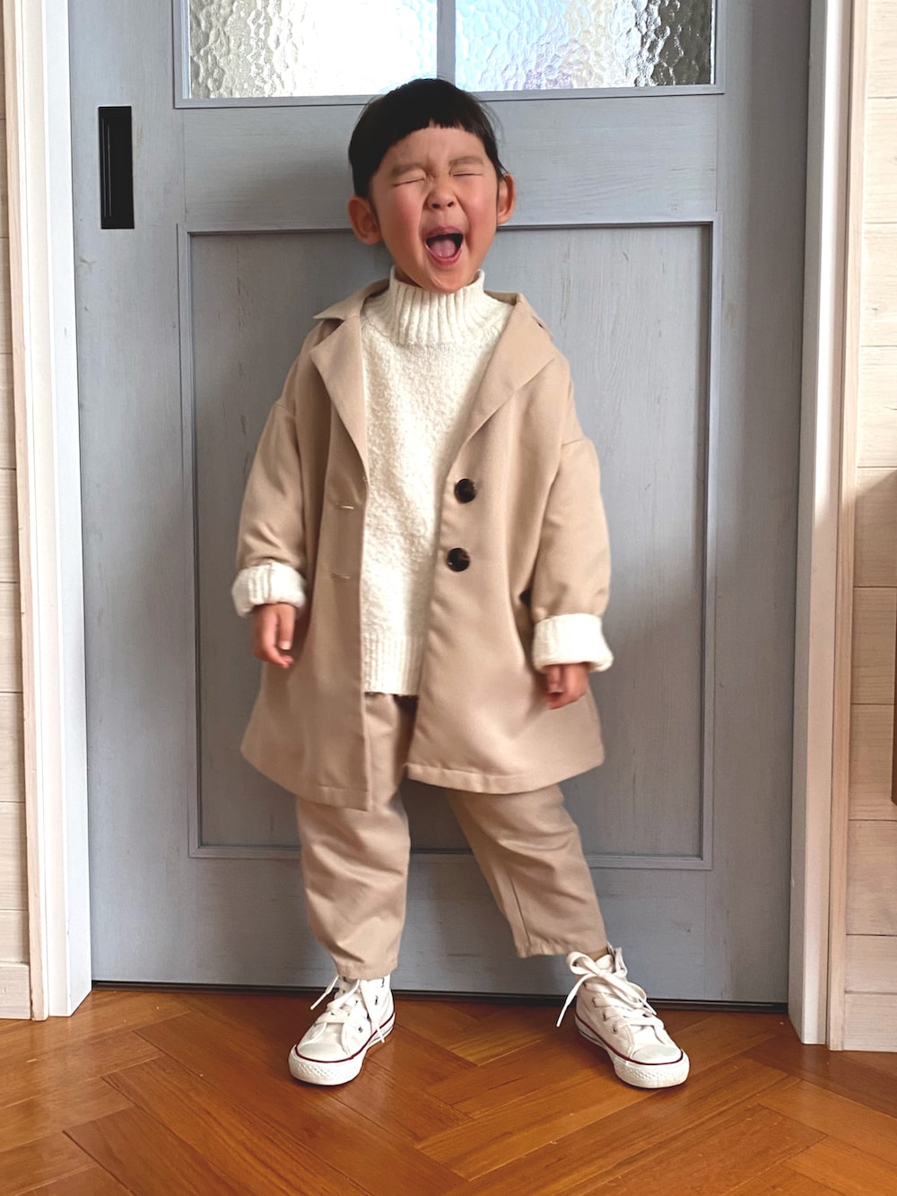 ベージュ系のチェスターコート、ホワイト系のスニーカー、ベージュ系のその他パンツを着用したキッズの冬コーディネートの2枚目の写真