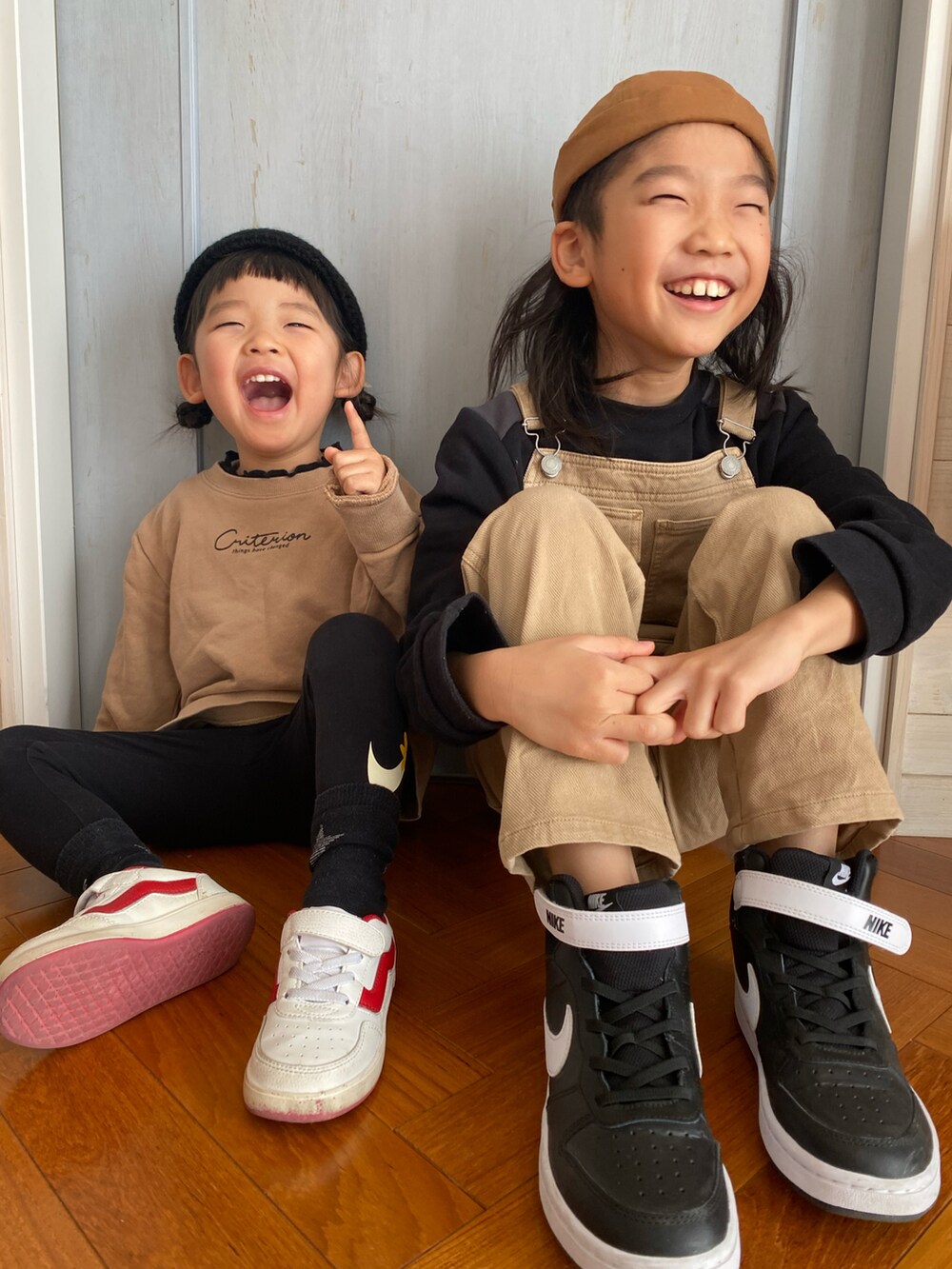ベージュ系のスウェット、ベージュ系のサロペット/オーバーオール、ブラック系のスニーカーを着用したキッズの冬コーディネートの2枚目の写真