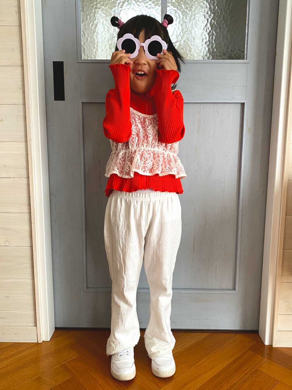 ホワイト系のアンサンブル、オレンジ系のトップス、ホワイト系のパンツを着用したキッズの春コーディネートの2枚目の写真