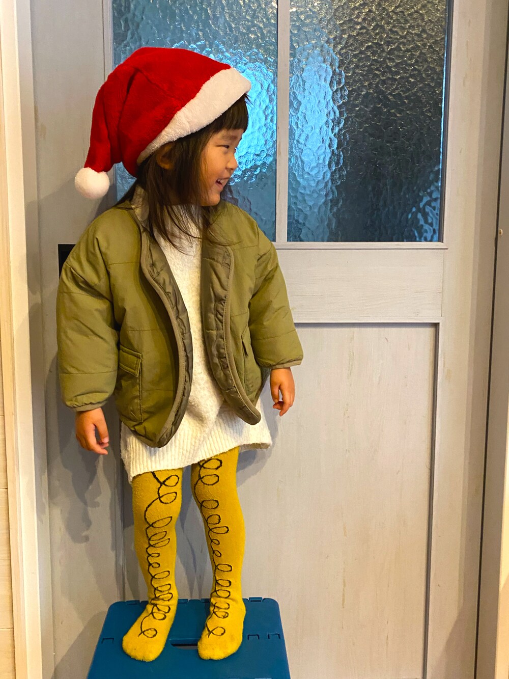 グリーン系のジャケット/アウター、ホワイト系のニット/セーター、レッド系の帽子を着用したキッズの冬コーディネートの2枚目の写真