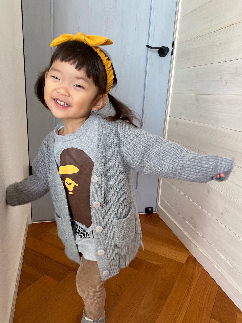 グレー系のジャケット/アウター、グレー系のスニーカー、イエロー系のヘアバンドを着用したキッズの秋コーディネートの2枚目の写真