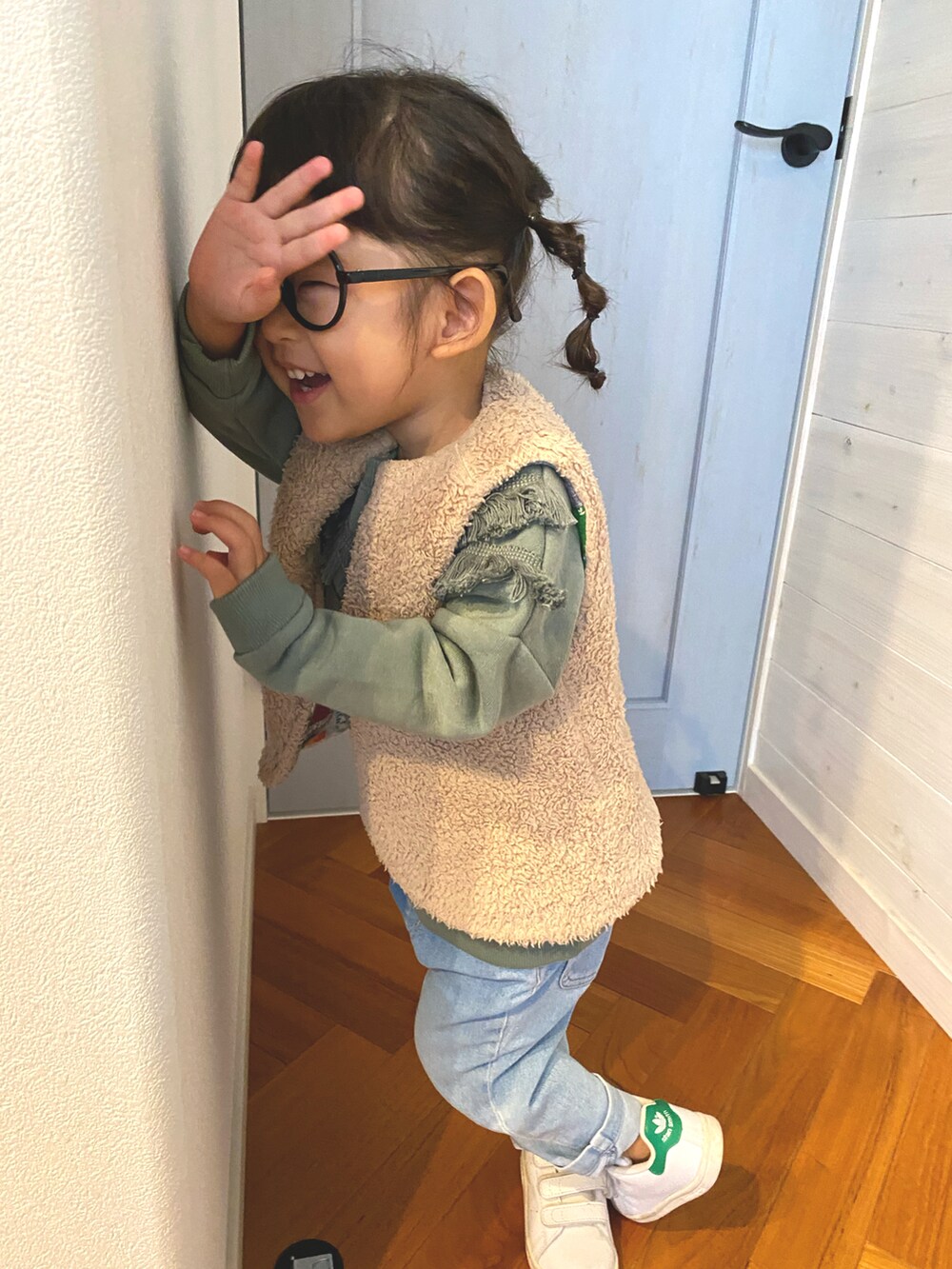 グリーン系のスウェット、ベージュ系のダウンベスト、ブラック系のメガネを着用したキッズの秋コーディネートの2枚目の写真