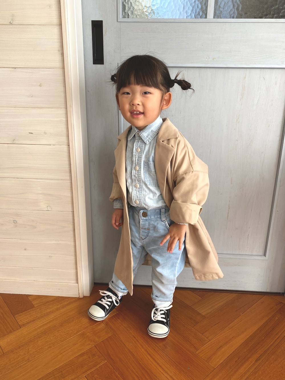 ベージュ系のチェスターコート、ブルー系のシャツ/ブラウス、ブラック系のスニーカーを着用したキッズの秋コーディネートの2枚目の写真
