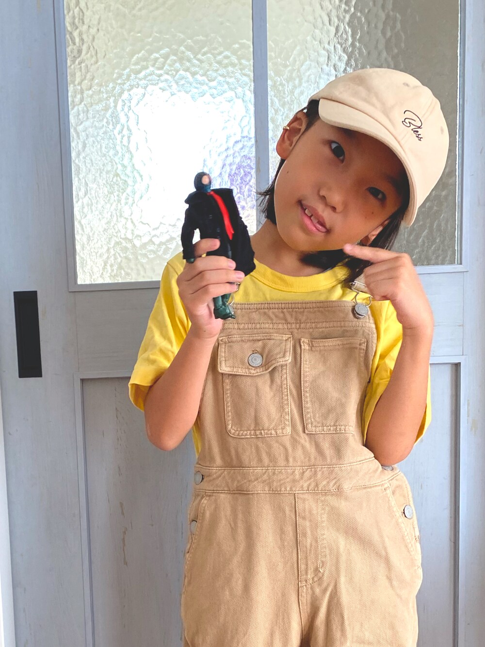 イエロー系のTシャツ/カットソー、ベージュ系のサロペット/オーバーオール、ベージュ系のキャップを着用したキッズの夏コーディネートの3枚目の写真
