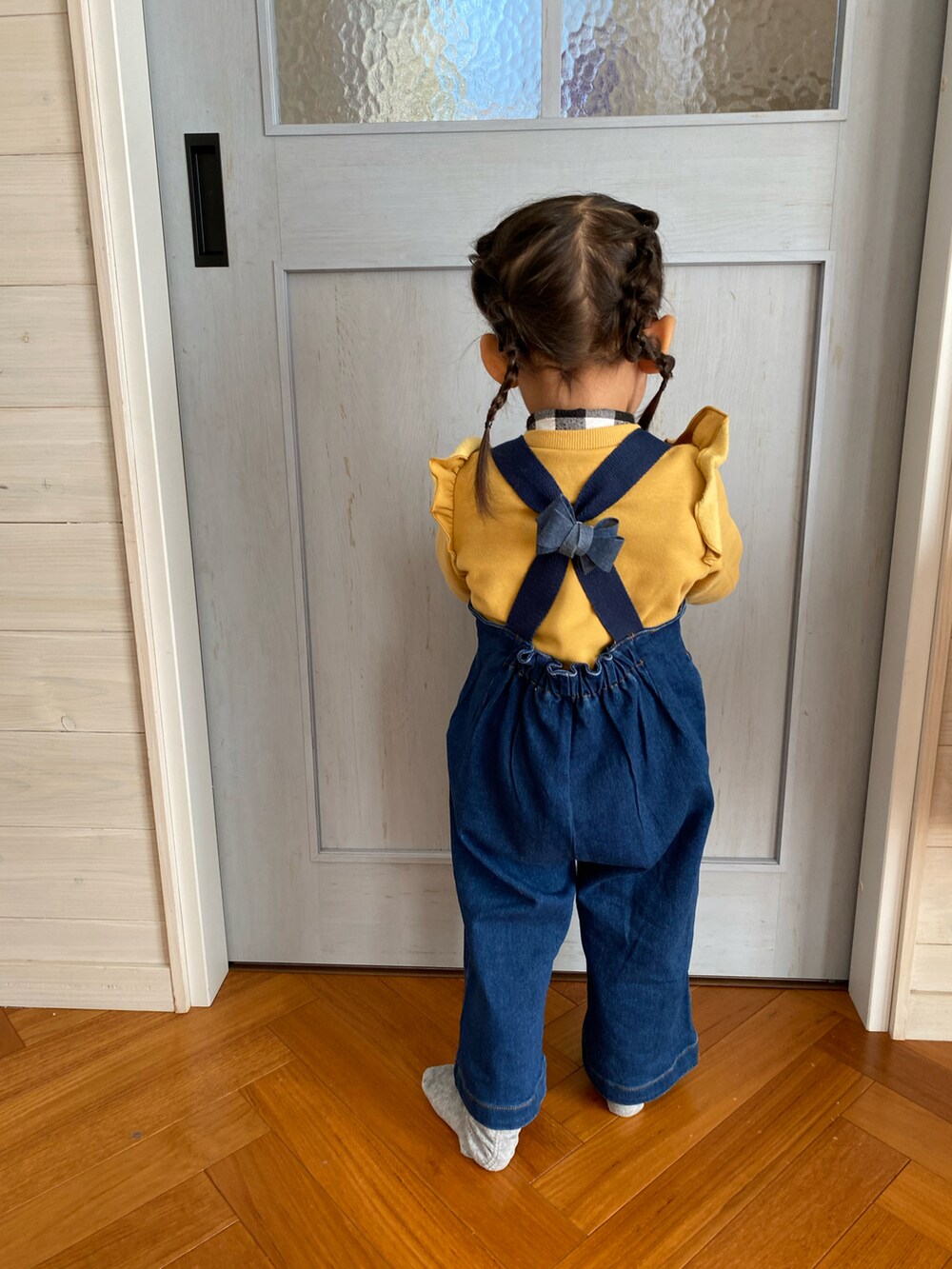 ブルー系のサロペット/オーバーオール、イエロー系のスウェット、ピンク系のソックス/靴下を着用したキッズの冬コーディネートの3枚目の写真