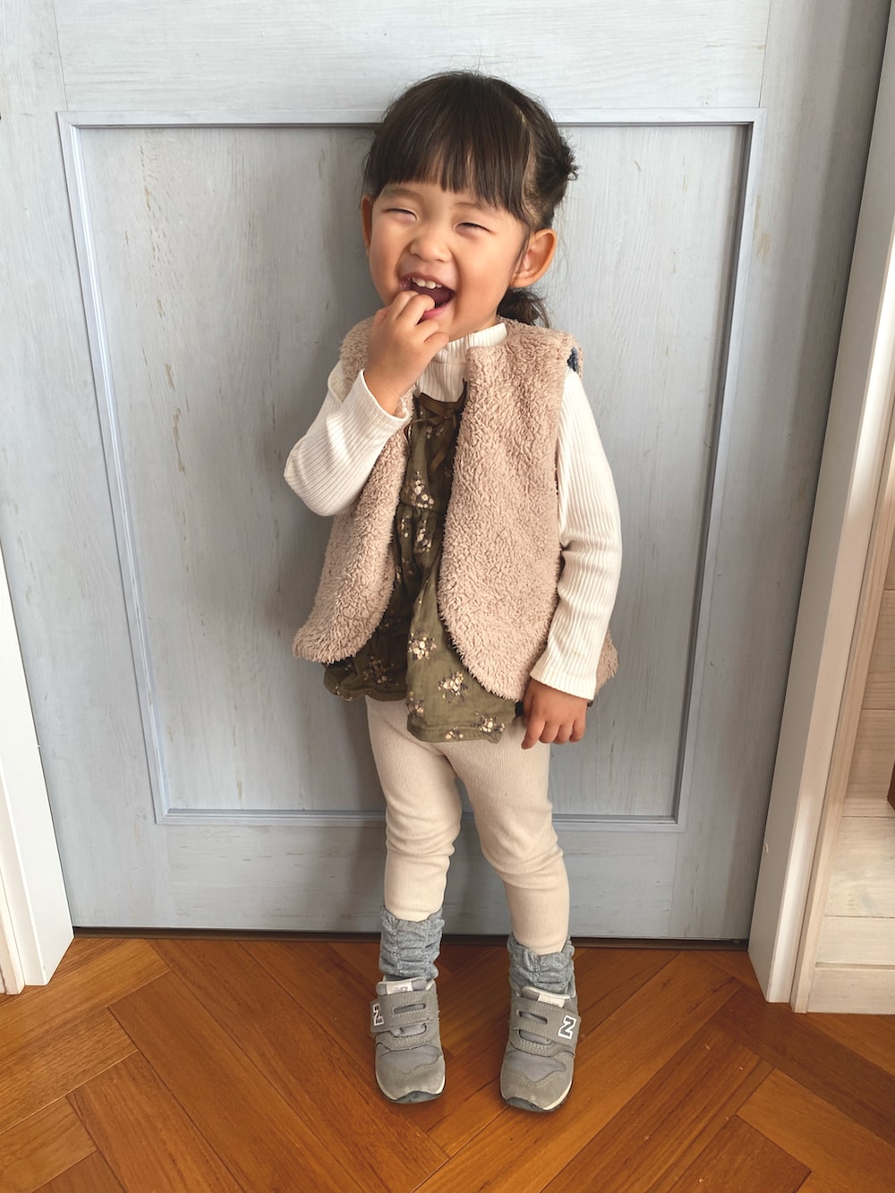 グリーン系のTシャツ/カットソー、グレー系のスニーカー、ベージュ系のダウンベストを着用したキッズの秋コーディネートの2枚目の写真