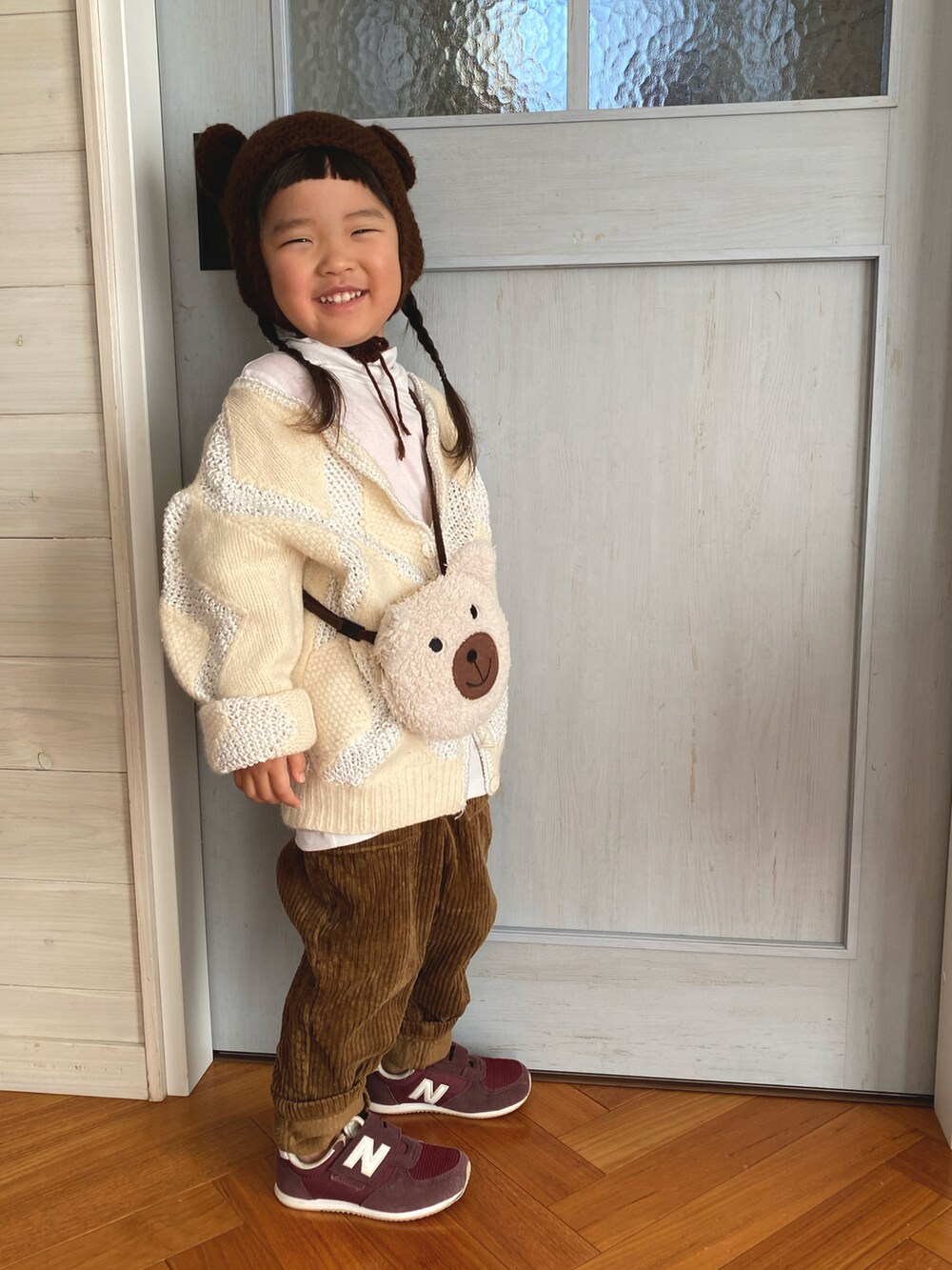 ベージュ系のハンドバッグ、ブラウン系のパンツ、レッド系のスニーカーを着用したキッズの冬コーディネートの3枚目の写真