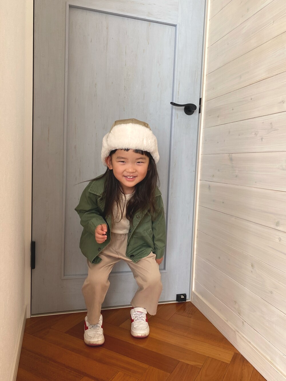 ホワイト系のスウェット、ホワイト系のスニーカー、グリーン系のカバーオールを着用したキッズの冬コーディネートの2枚目の写真