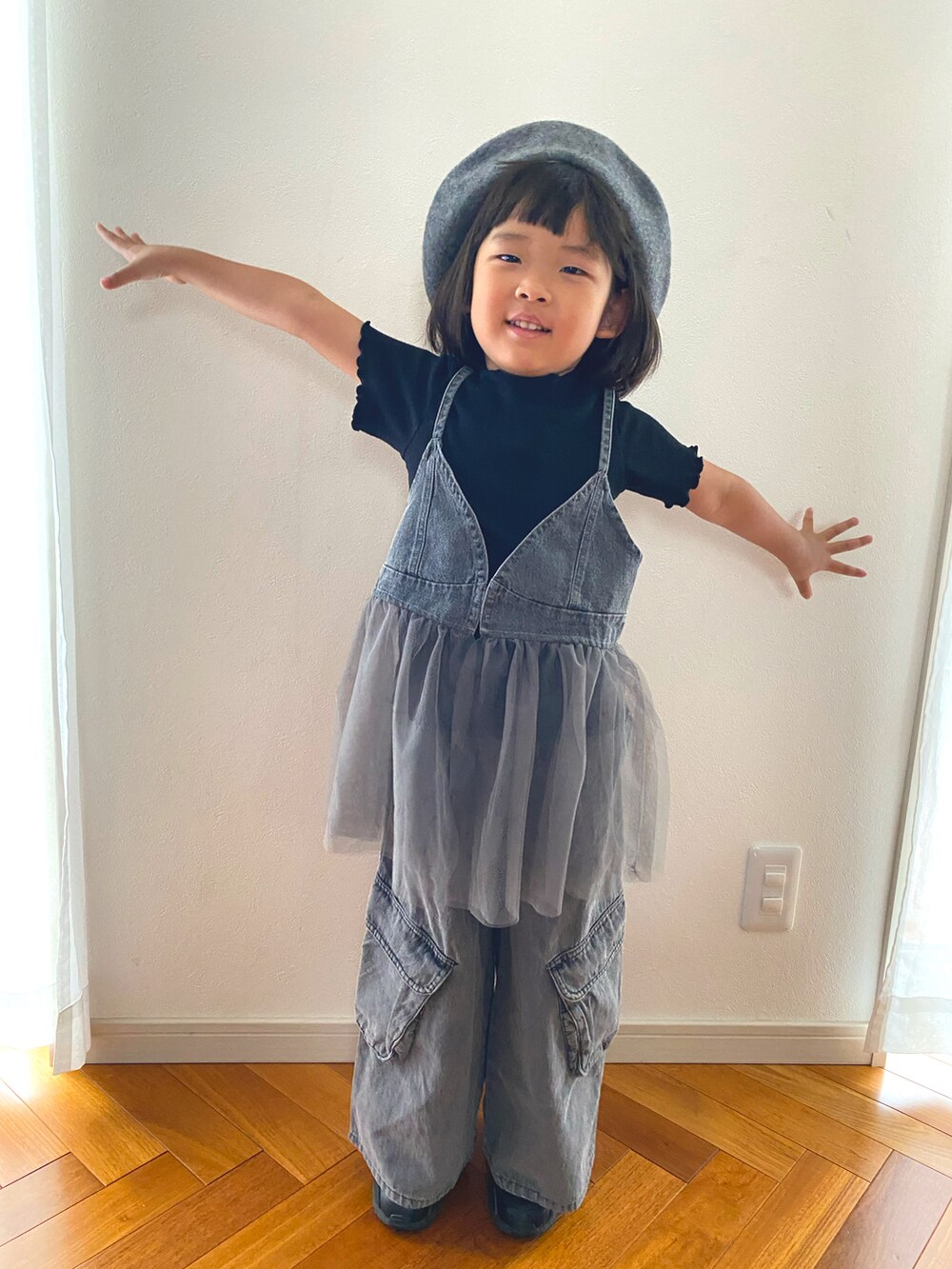 グレー系のキャミソール、グレー系のデニムパンツ、ブラック系のスニーカーを着用したキッズの秋コーディネートの2枚目の写真