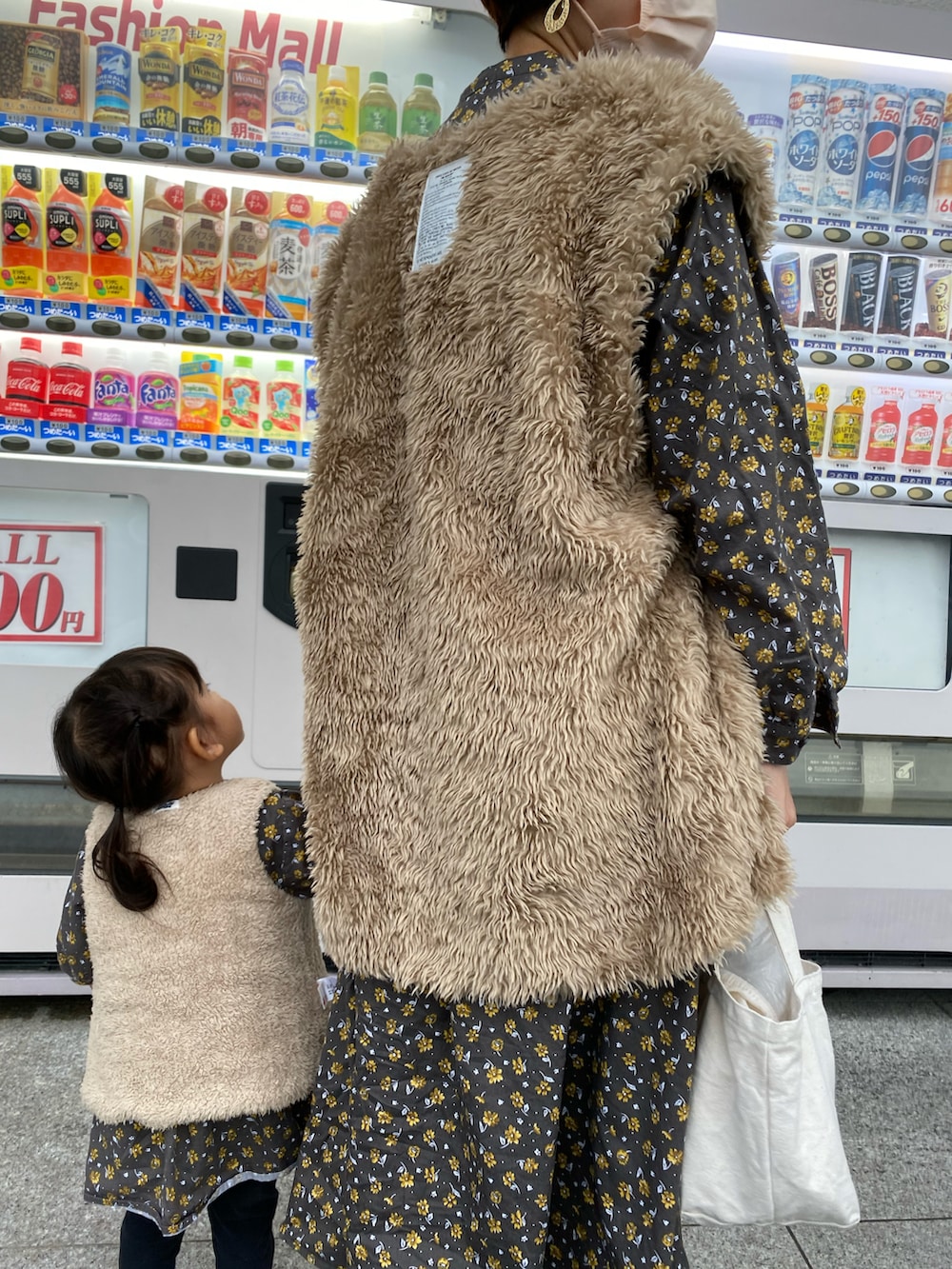 ベージュ系のダウンベスト、ベージュ系のベスト、グレー系のワンピースを着用したキッズの秋コーディネートの2枚目の写真