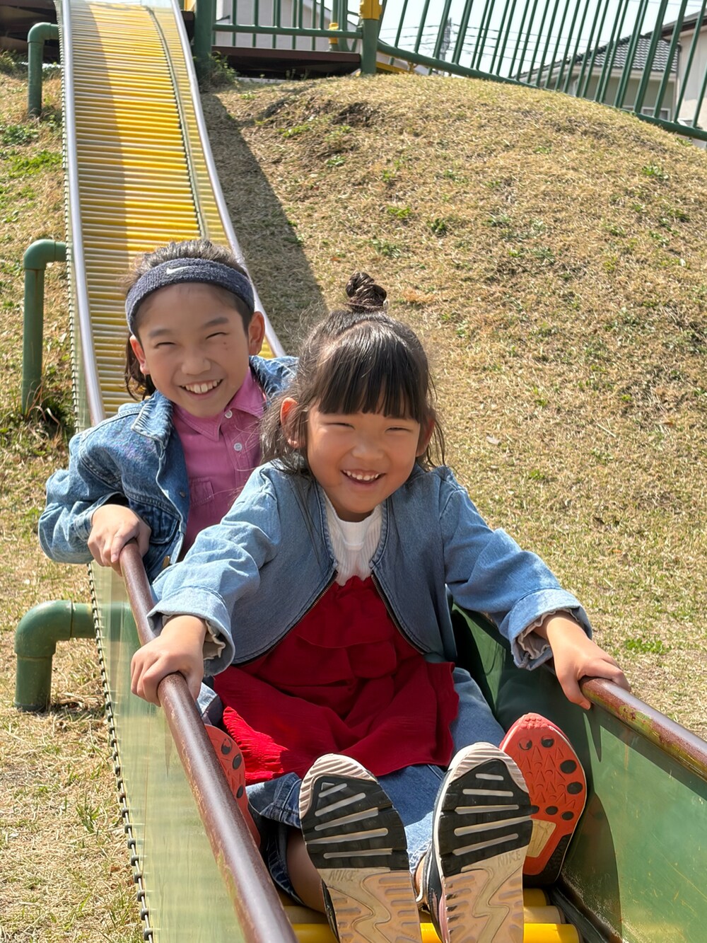 レッド系のワンピース、ホワイト系のスニーカー、ブルー系のデニムジャケットを着用したキッズの春コーディネートの2枚目の写真