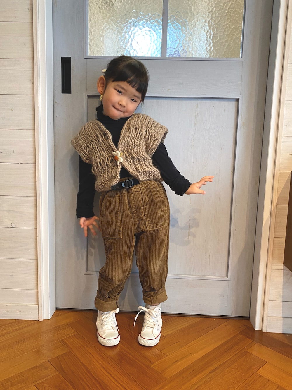ベージュ系のベスト、ブラウン系のパンツ、ホワイト系のスニーカーを着用したキッズの冬コーディネートの2枚目の写真