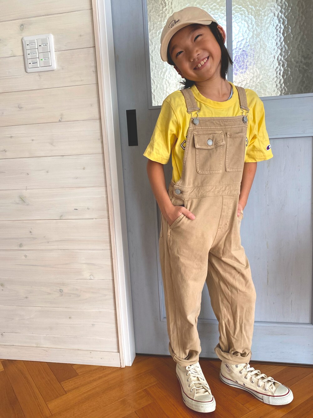 イエロー系のTシャツ/カットソー、ベージュ系のサロペット/オーバーオール、ベージュ系のキャップを着用したキッズの夏コーディネートの2枚目の写真