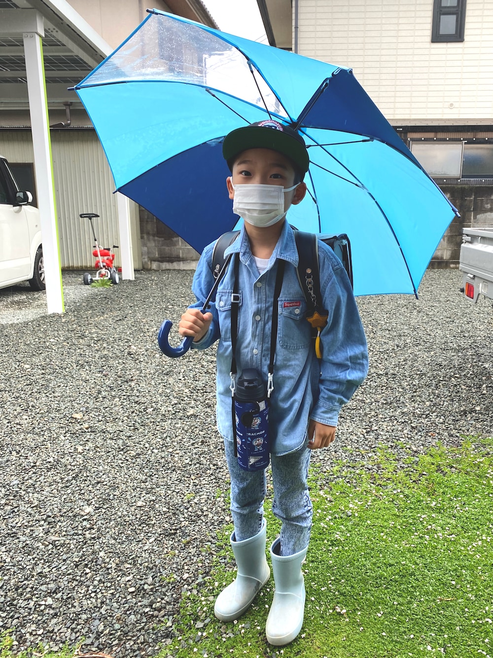 ブルー系のレインシューズ、ブルー系のランドセル、グレー系のデニムパンツを着用したキッズの春コーディネートの2枚目の写真