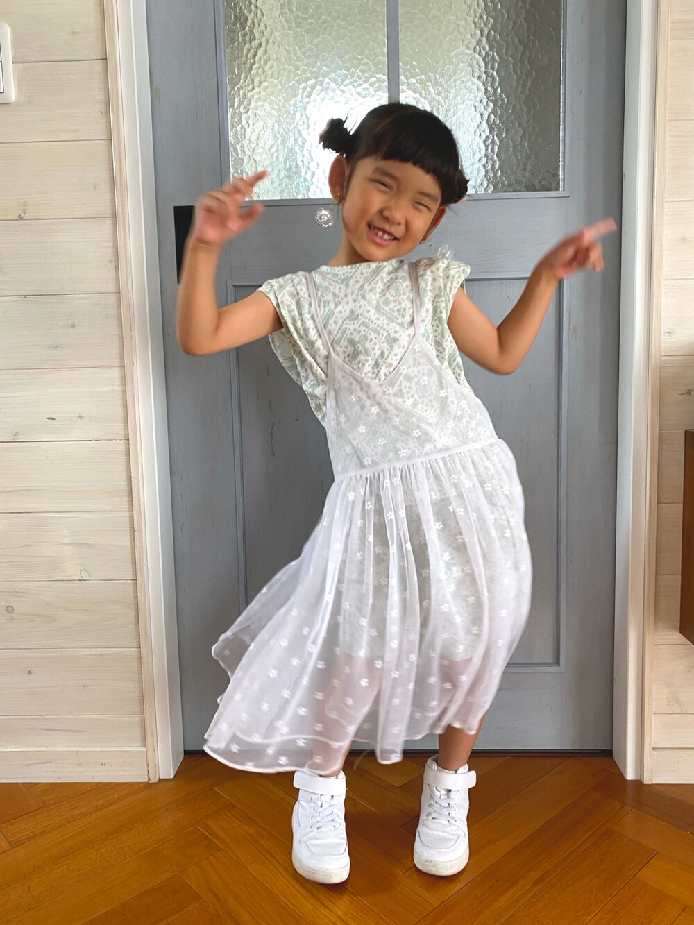 ホワイト系のワンピース、ホワイト系のスニーカー、グリーン系のタンクトップを着用したキッズの夏コーディネートの2枚目の写真