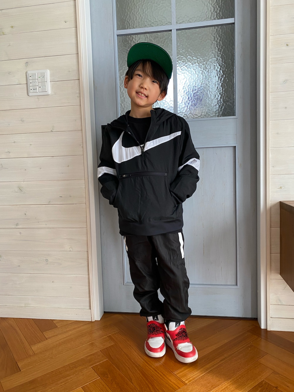 ブラック系のマウンテンパーカー、ブラック系のその他パンツ、レッド系のスニーカーを着用したキッズの冬コーディネートの2枚目の写真