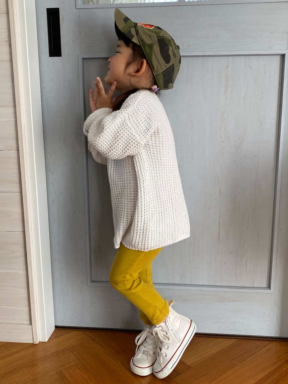 ホワイト系のスニーカー、イエロー系のパンツ、グリーン系のキャップを着用したキッズの春コーディネートの3枚目の写真