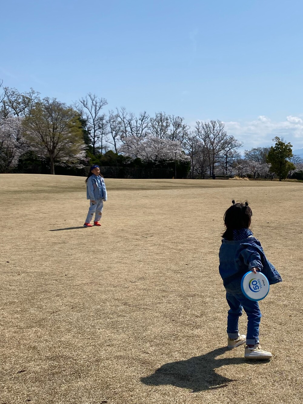 ブルー系のデニムジャケット、ブルー系のデニムパンツ、ホワイト系のアンサンブルを着用したキッズの春コーディネートの4枚目の写真