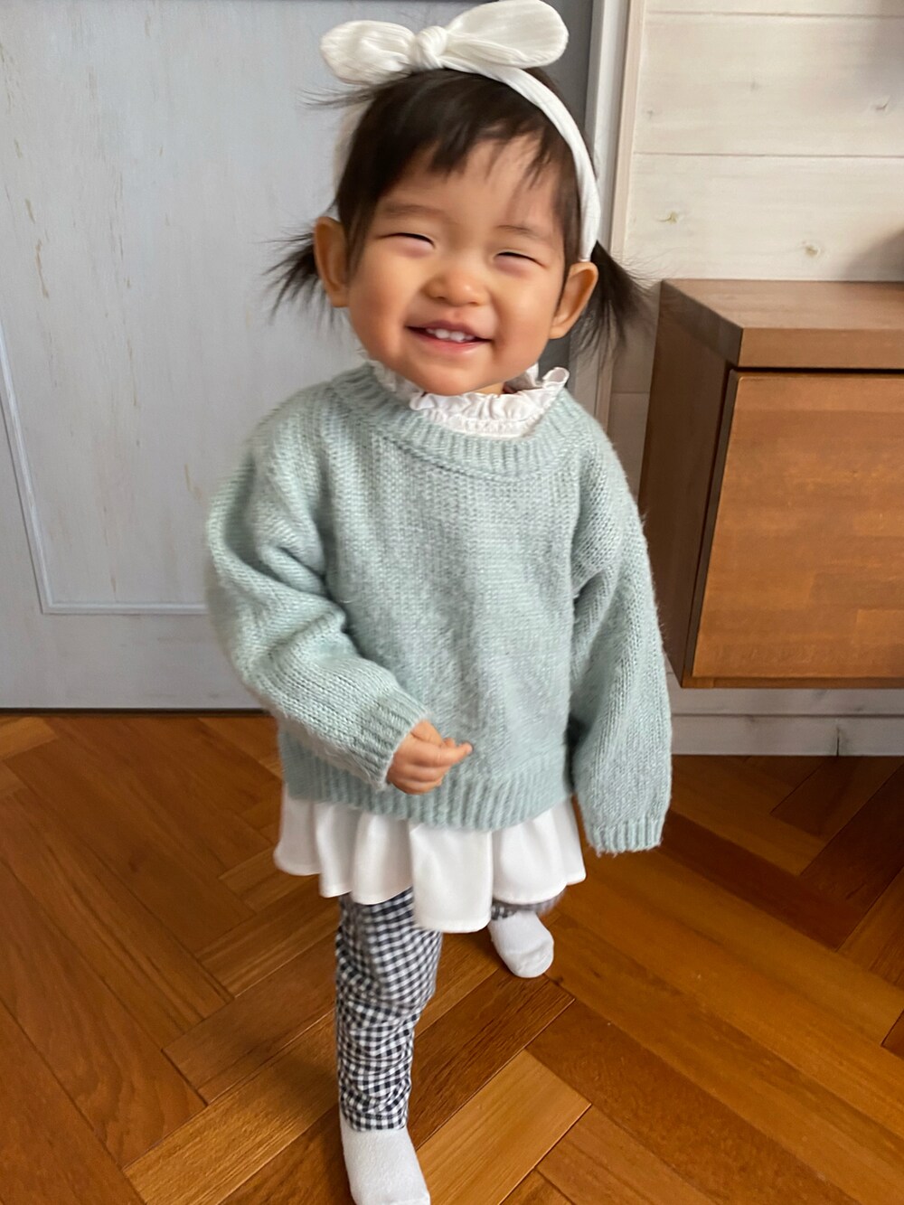 ベージュ系のチェスターコート、グリーン系のニット/セーター、ブラック系のレギンス/スパッツを着用したキッズの冬コーディネートの2枚目の写真