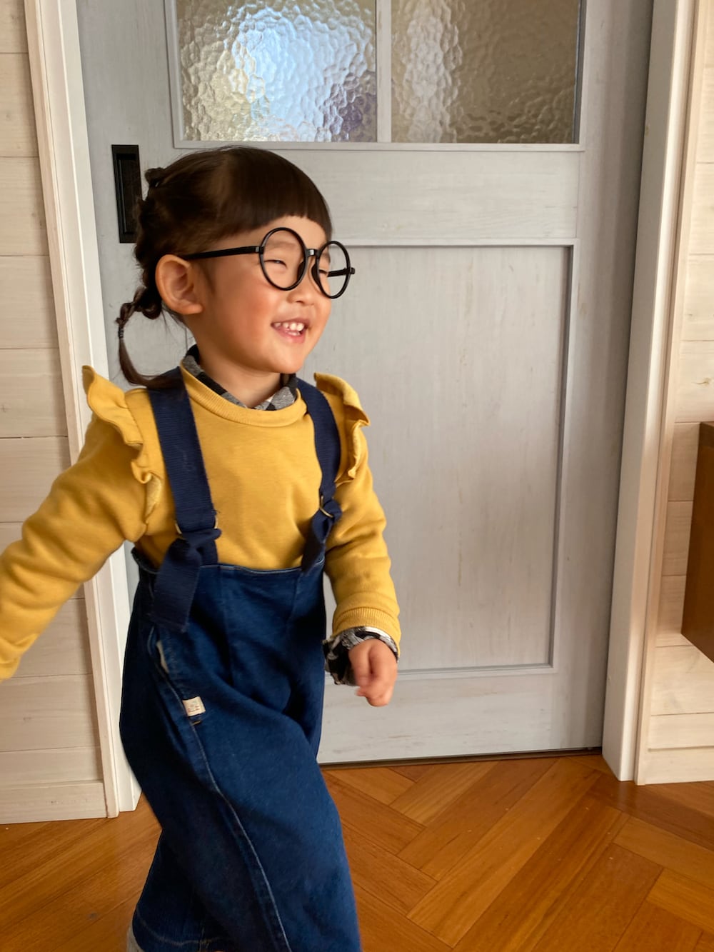 ブルー系のサロペット/オーバーオール、イエロー系のスウェット、ピンク系のソックス/靴下を着用したキッズの冬コーディネートの2枚目の写真