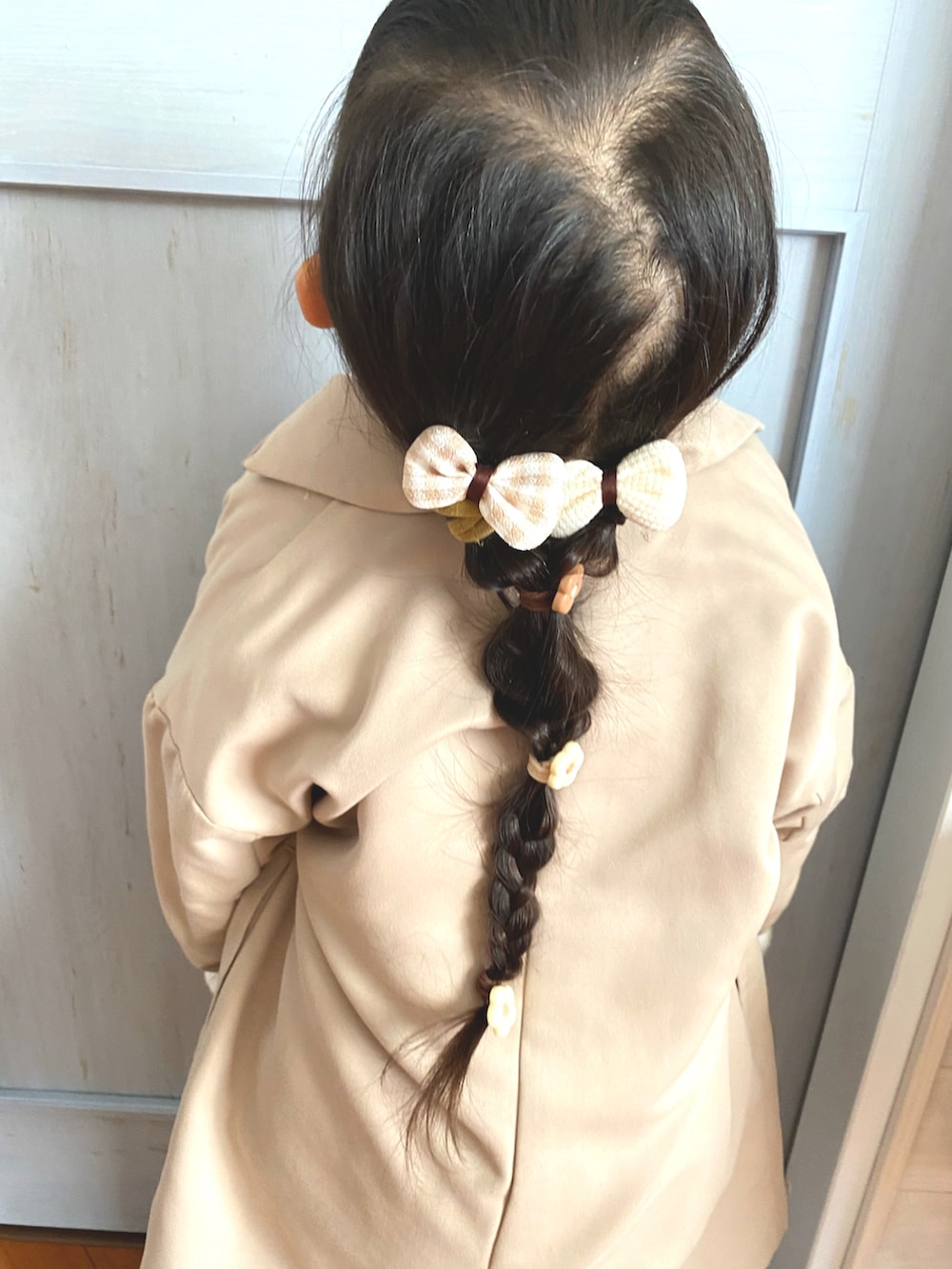 ベージュ系のチェスターコート、ホワイト系のスニーカー、ベージュ系のその他パンツを着用したキッズの冬コーディネートの3枚目の写真