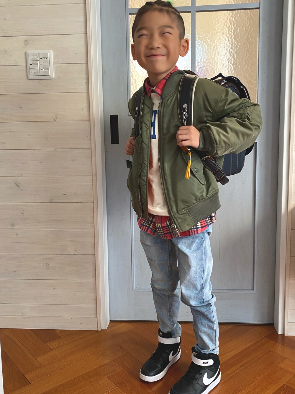 グリーン系のミリタリージャケット、ブルー系のデニムパンツ、ブラック系のスニーカーを着用したキッズの秋コーディネートの3枚目の写真