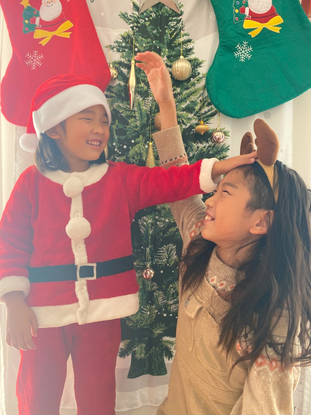 ベージュ系のニット/セーター、ベージュ系のサロペット/オーバーオール、レッド系のコスチューム/パーティーグッズを着用したキッズの冬コーディネートの2枚目の写真