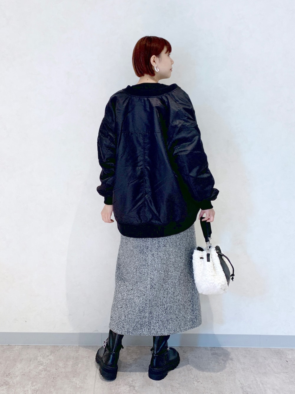 ホワイト系のショルダーバッグ、ブラック系のブーツ、ブラック系のスカートを着用したレディースの秋コーディネートの3枚目の写真