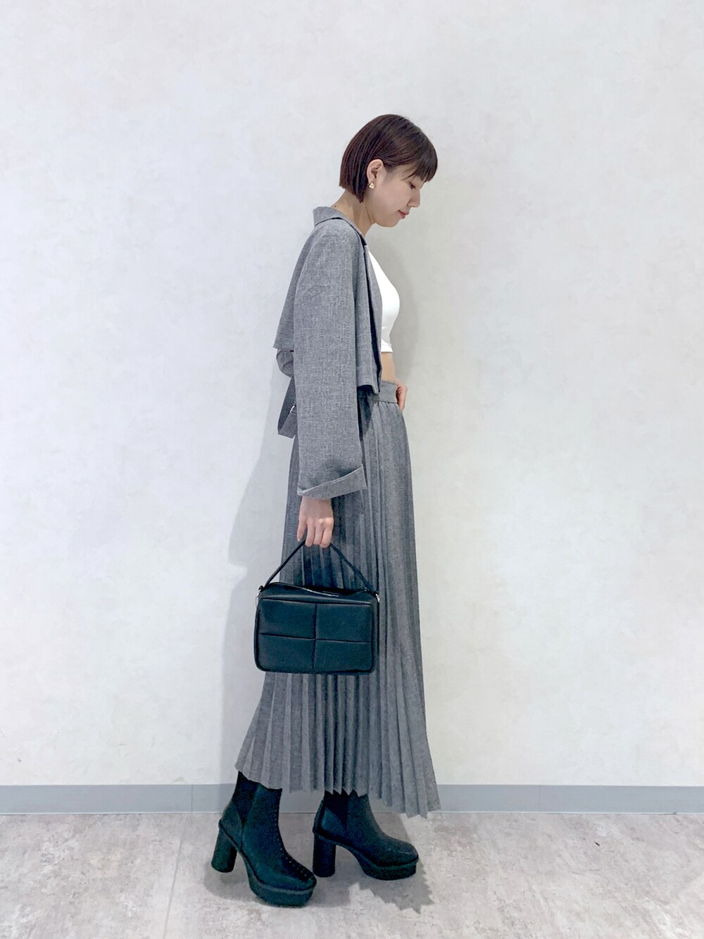 グレー系のスカート、ブラック系のショルダーバッグ、ブラック系のブーツを着用したレディースの夏コーディネートの3枚目の写真