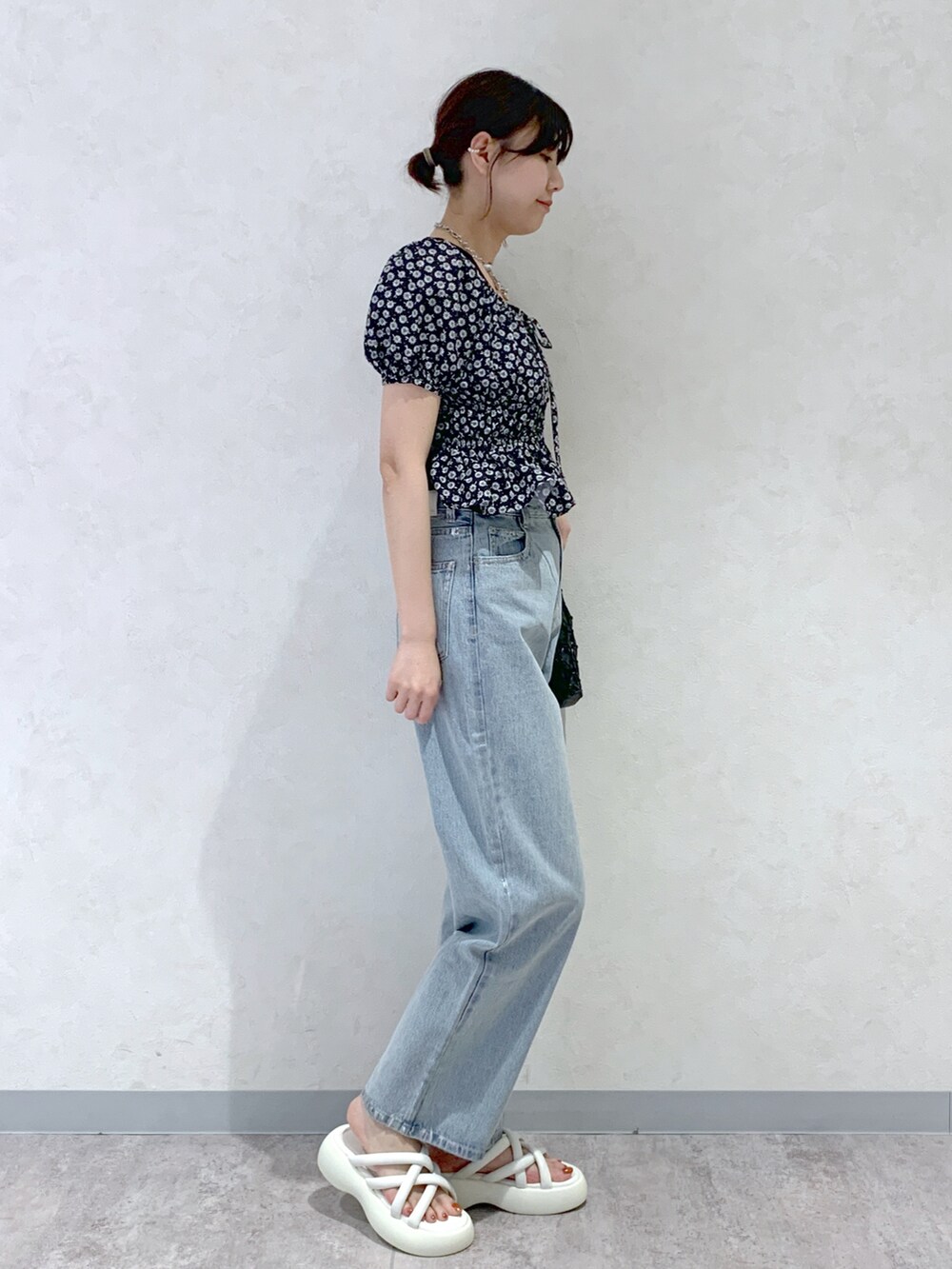 ブルー系のデニムパンツ、ホワイト系のサンダル、ブラック系のシャツ/ブラウスを着用したレディースの春コーディネートの3枚目の写真