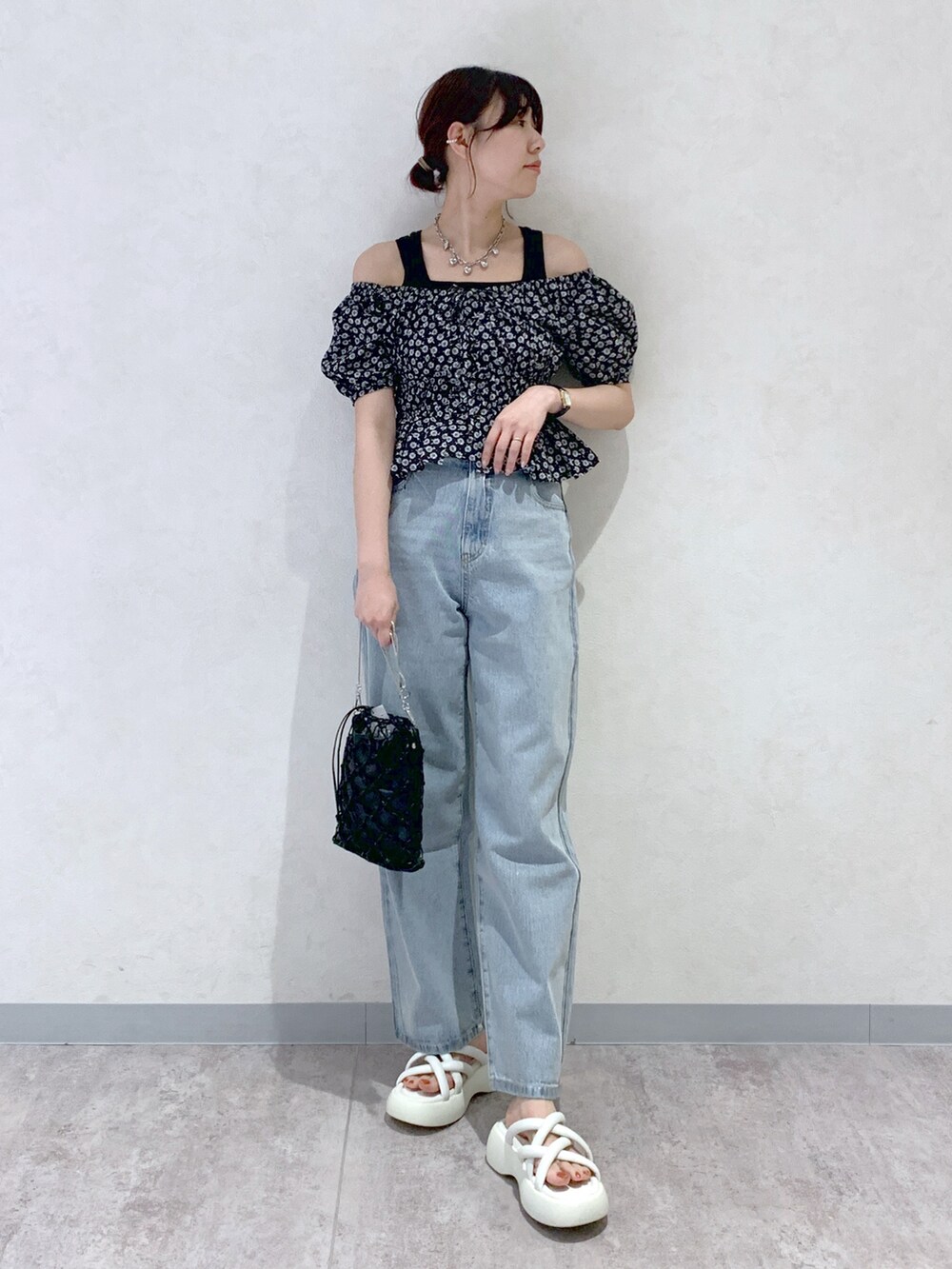 ブルー系のデニムパンツ、ホワイト系のサンダル、ブラック系のシャツ/ブラウスを着用したレディースの春コーディネートの2枚目の写真