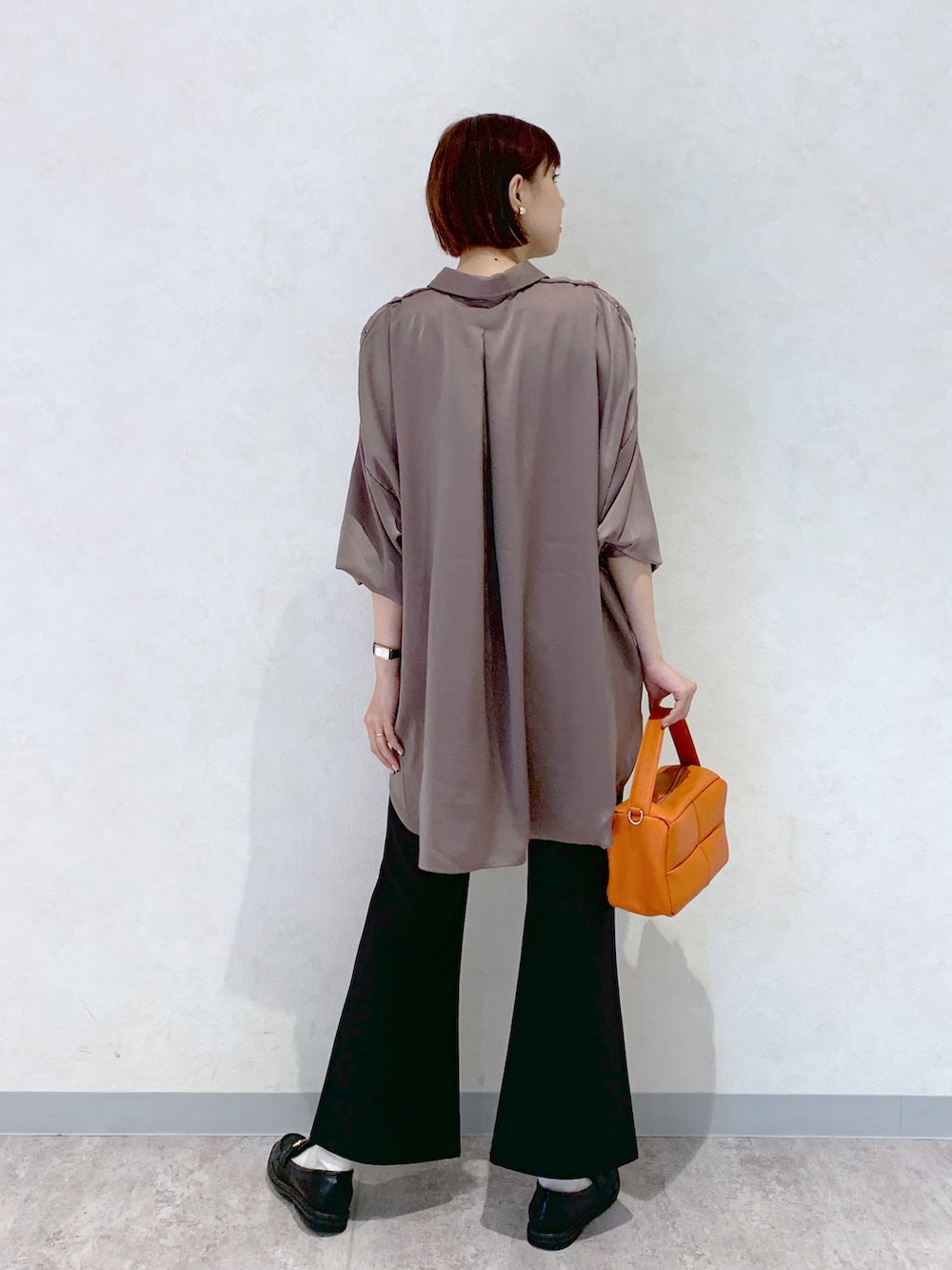 オレンジ系のショルダーバッグ、ブラック系のローファー、ブラック系のスラックスを着用したレディースの夏コーディネートの3枚目の写真