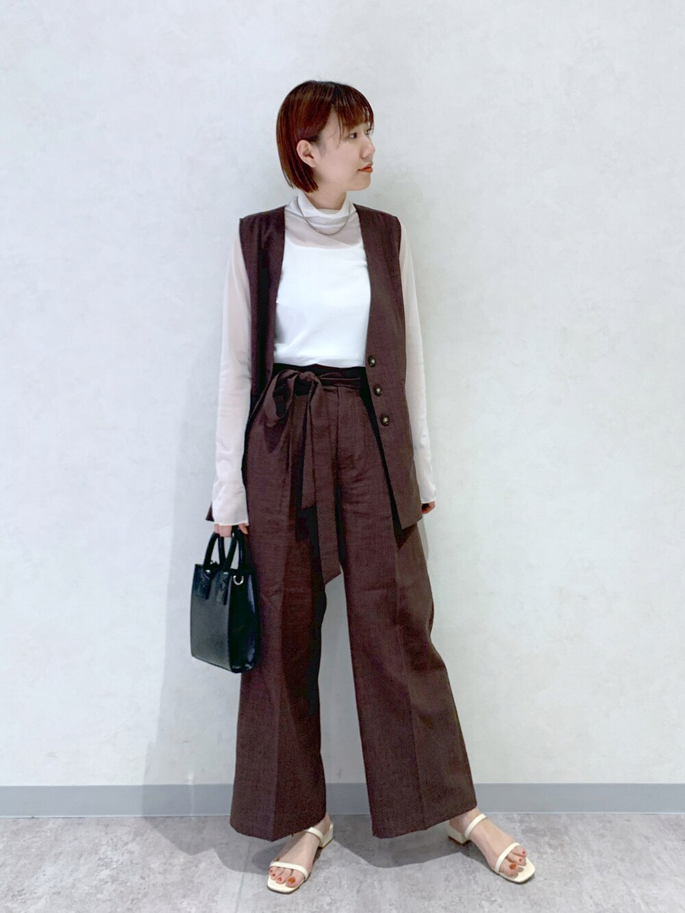 ホワイト系のサンダル、ブラック系のショルダーバッグ、ブラウン系のその他パンツを着用したレディースの春コーディネートの3枚目の写真