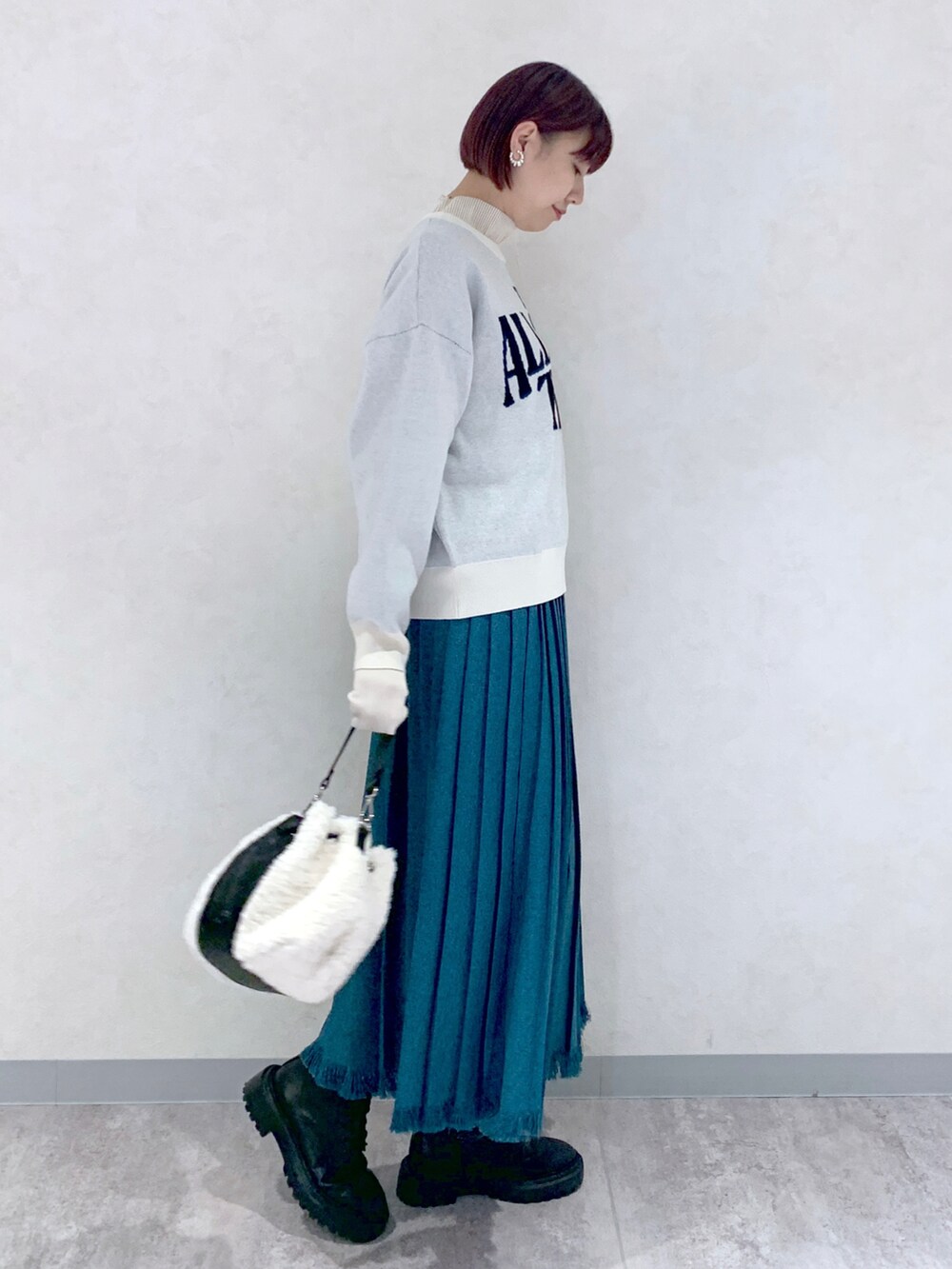 ホワイト系のニット/セーター、ブルー系のスカート、ブラック系のブーツを着用したレディースの秋コーディネートの3枚目の写真