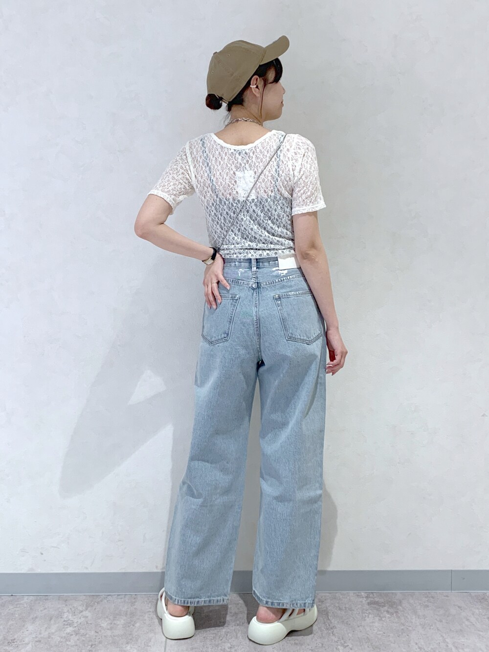 ホワイト系のサンダル、ブルー系のデニムパンツ、ブラック系のショルダーバッグを着用したレディースの春コーディネートの4枚目の写真