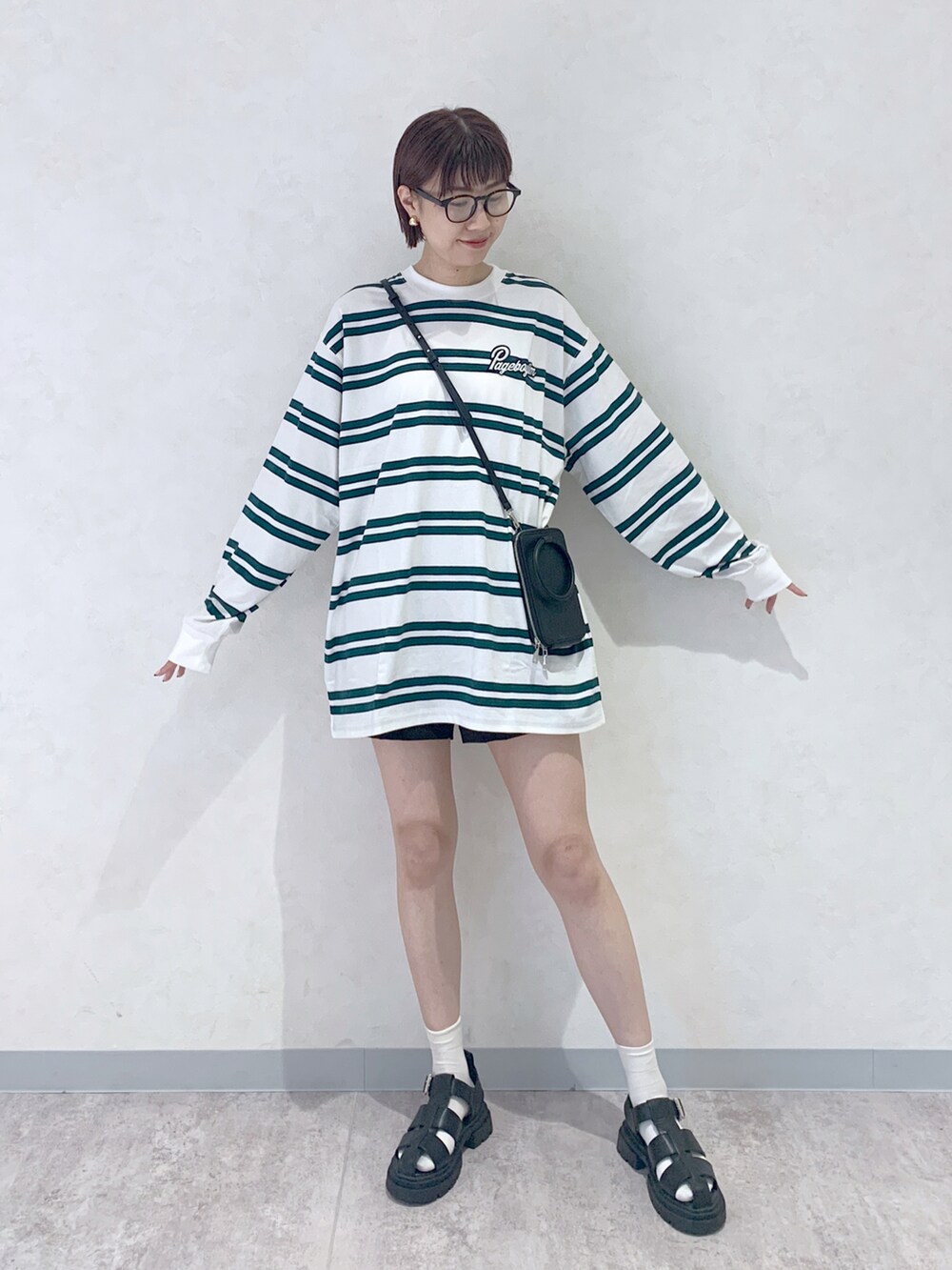 ブラック系のサンダル、ブラック系のショルダーバッグ、ホワイト系のTシャツ/カットソーを着用したレディースの夏コーディネートの2枚目の写真