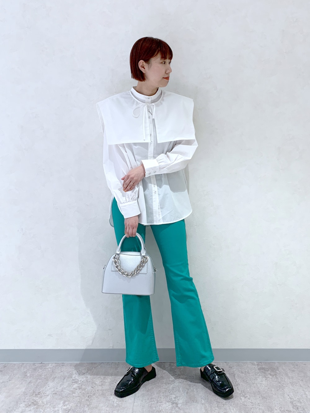 シルバー系のショルダーバッグ、ブラック系のローファー、グリーン系のデニムパンツを着用したレディースの春コーディネートの4枚目の写真