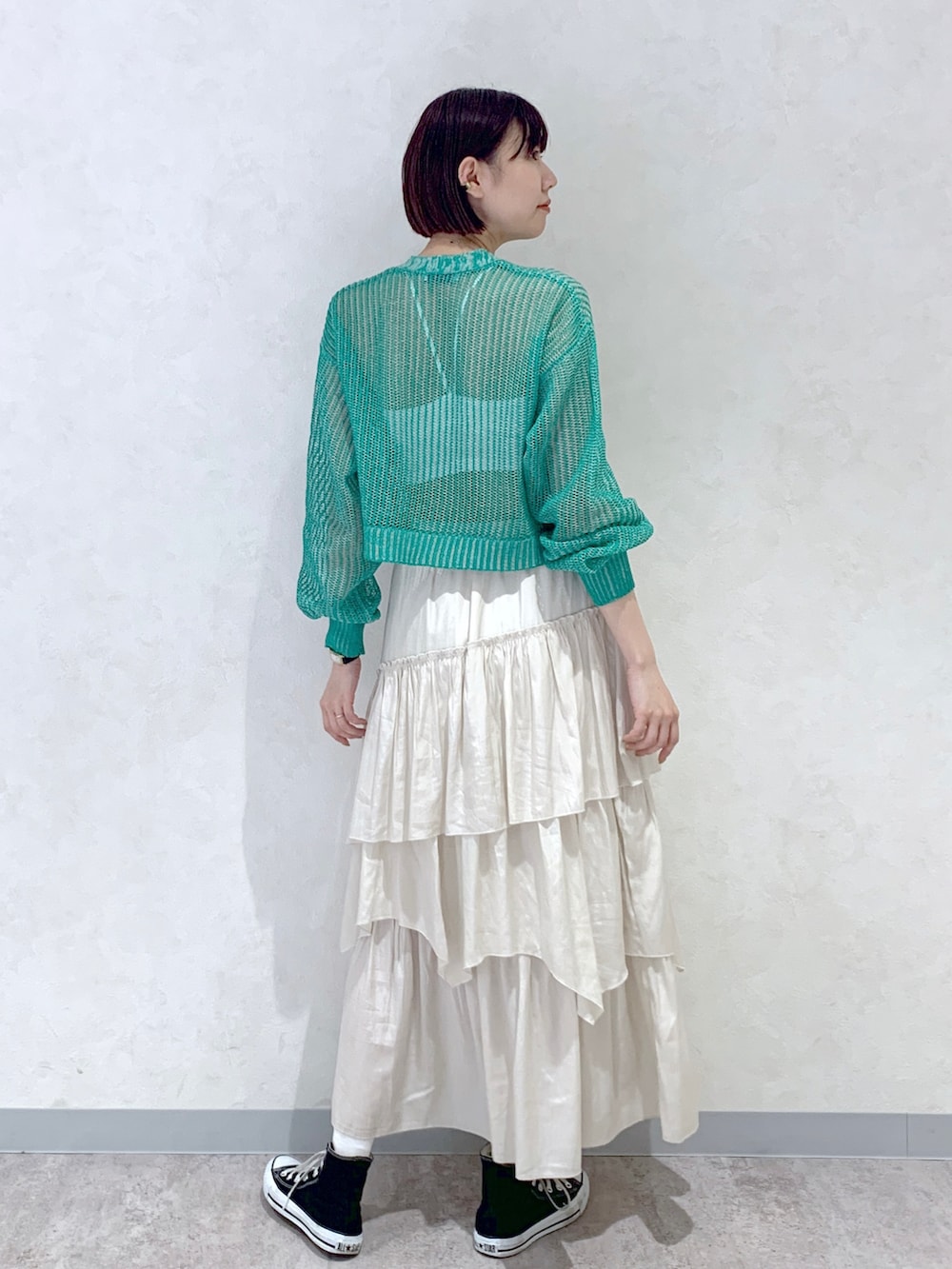 ベージュ系のスカート、ホワイト系のキャミソール、グリーン系のカーディガン/ボレロを着用したレディースの春コーディネートの3枚目の写真