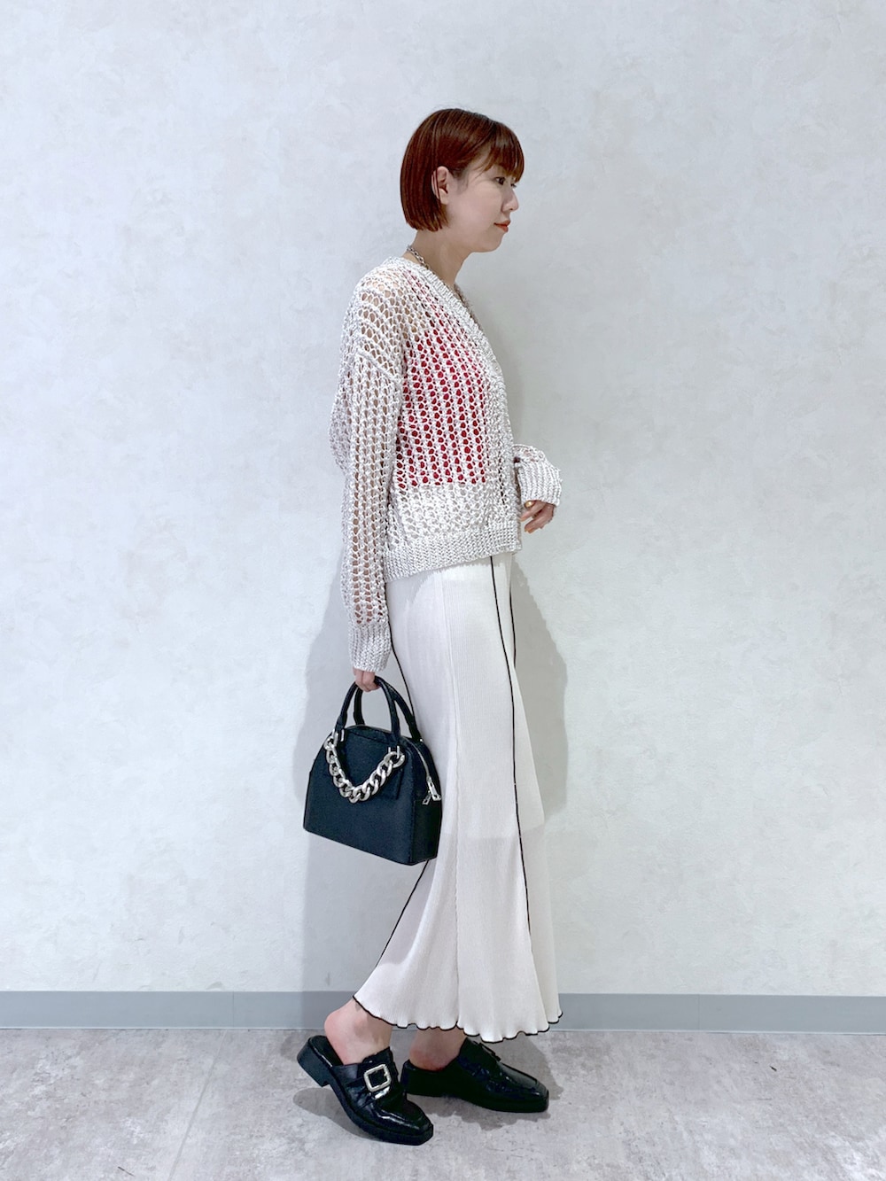 ブラック系のショルダーバッグ、ブラック系のローファー、ホワイト系のカーディガン/ボレロを着用したレディースの春コーディネートの3枚目の写真