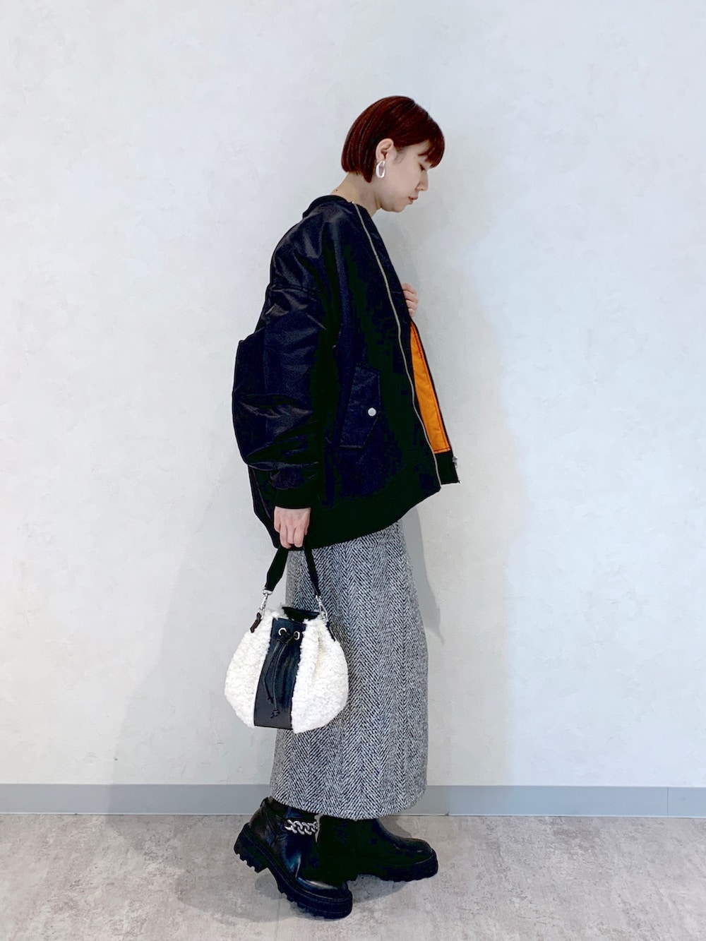 ホワイト系のショルダーバッグ、ブラック系のブーツ、ブラック系のスカートを着用したレディースの秋コーディネートの2枚目の写真