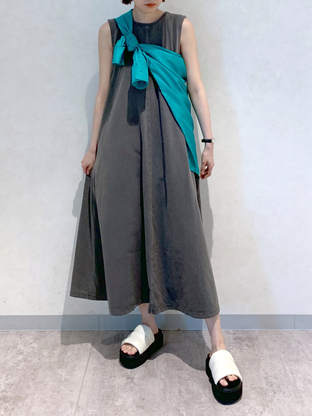 グレー系のワンピース、ホワイト系のサンダル、グリーン系のシャツ/ブラウスを着用したレディースの春コーディネートの2枚目の写真