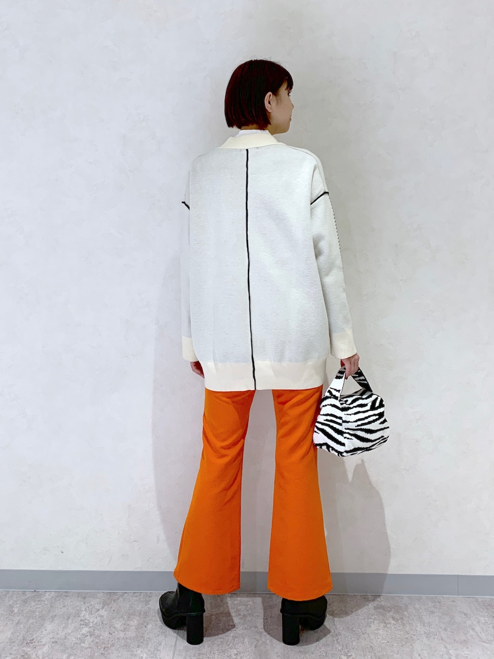 オレンジ系のスラックス、ブラック系のブーツ、その他のバッグを着用したレディースの秋コーディネートの4枚目の写真