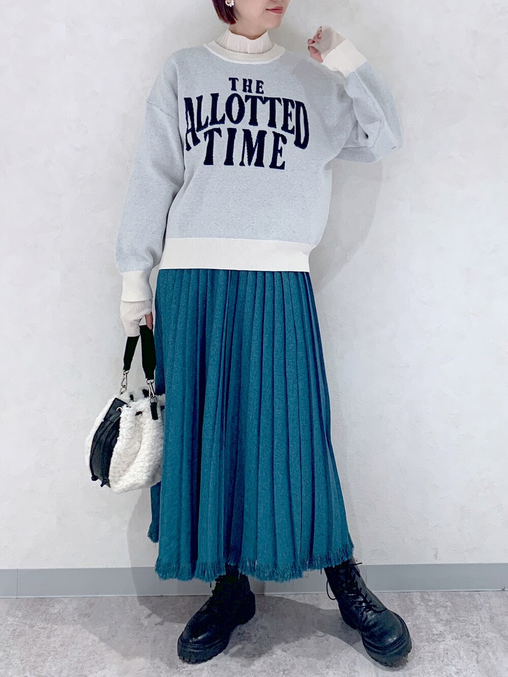 ホワイト系のニット/セーター、ブルー系のスカート、ブラック系のブーツを着用したレディースの秋コーディネートの2枚目の写真