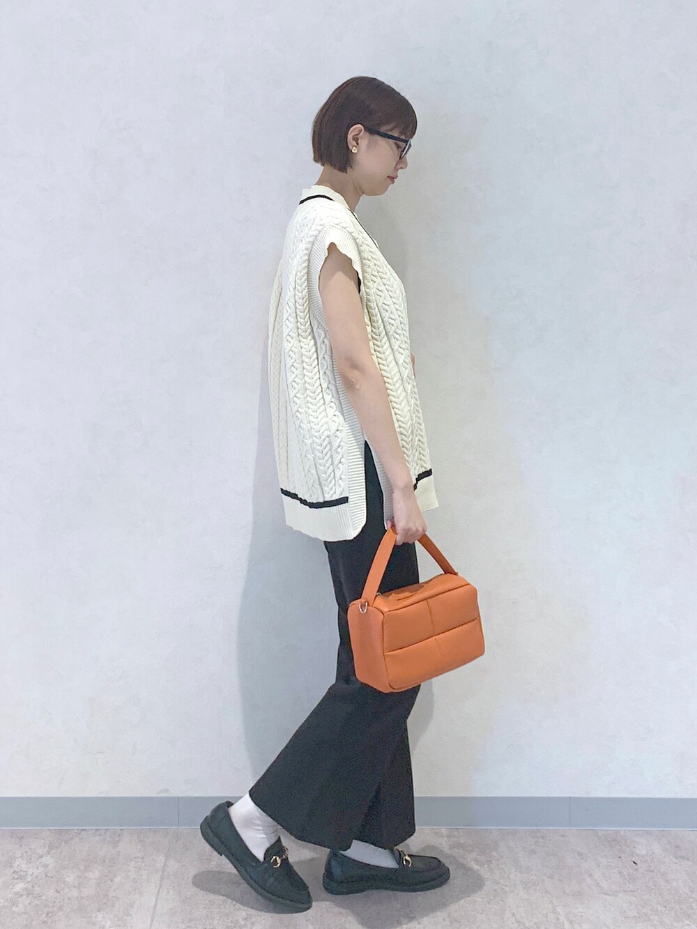 オレンジ系のショルダーバッグ、ブラック系のローファー、ブラック系のスラックスを着用したレディースの夏コーディネートの3枚目の写真