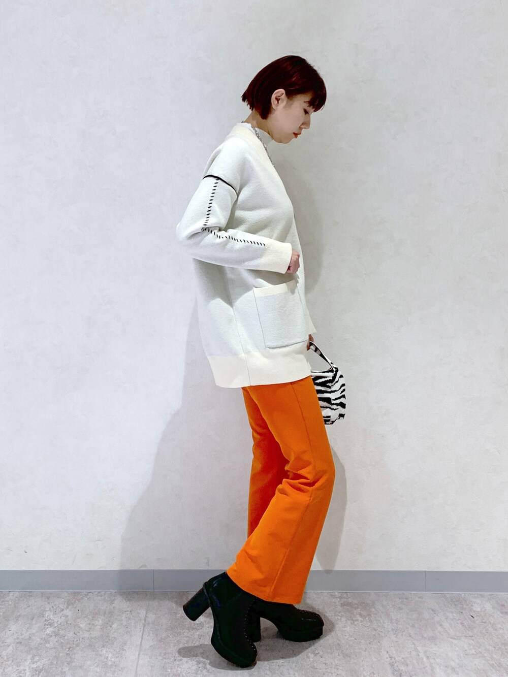 オレンジ系のスラックス、ブラック系のブーツ、その他のバッグを着用したレディースの秋コーディネートの3枚目の写真