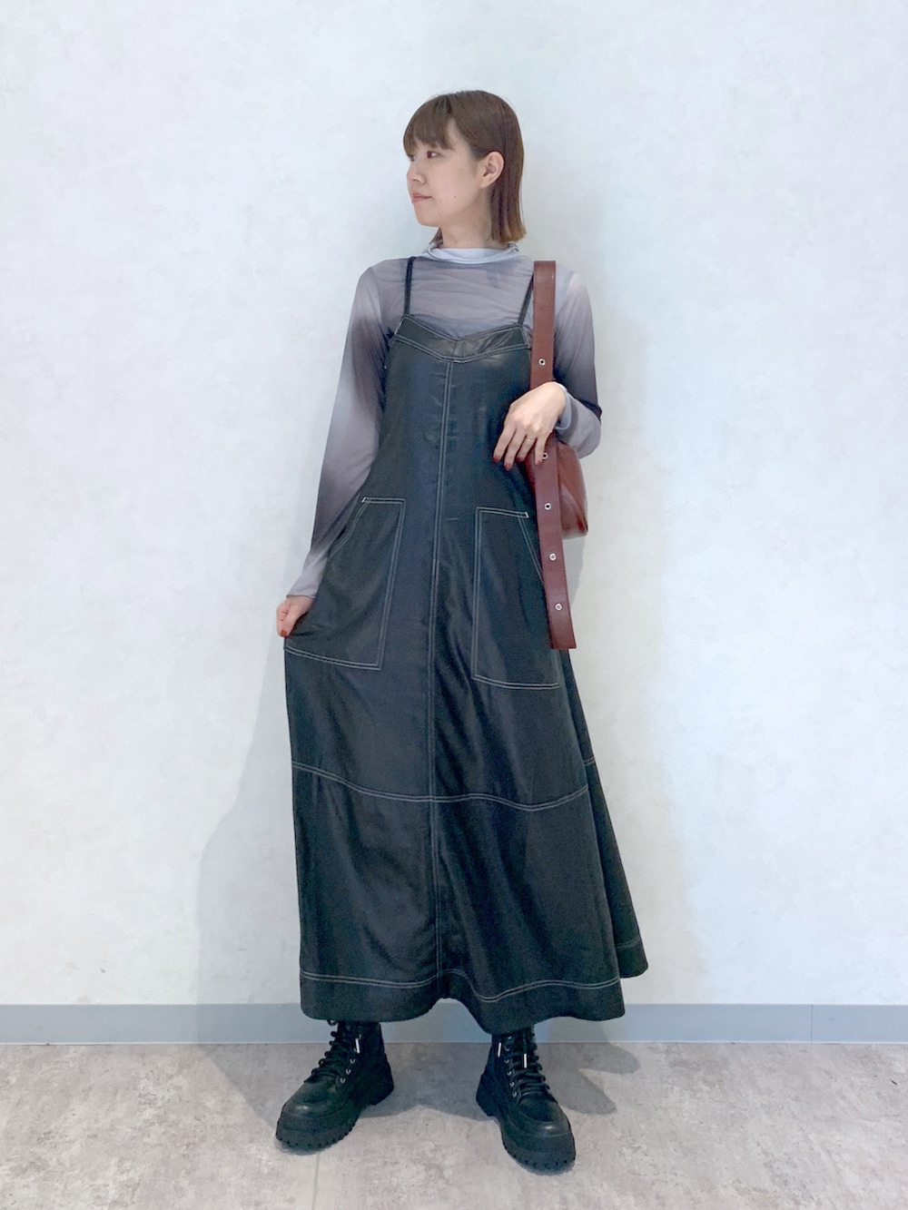 ブラック系のワンピース、ブラック系のブーツ、ブラウン系のショルダーバッグを着用したレディースの夏コーディネートの2枚目の写真