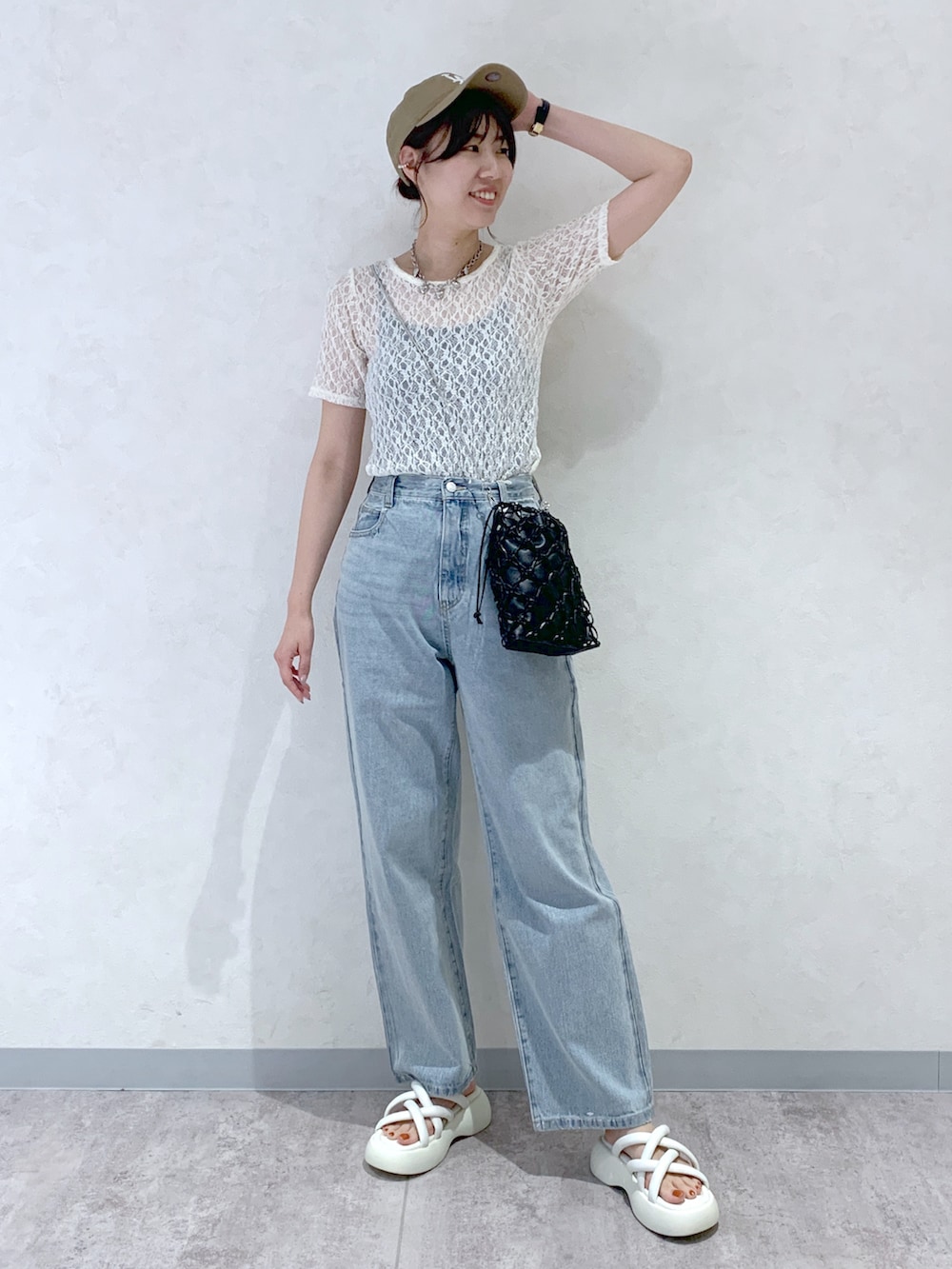 ホワイト系のサンダル、ブルー系のデニムパンツ、ブラック系のショルダーバッグを着用したレディースの春コーディネートの2枚目の写真