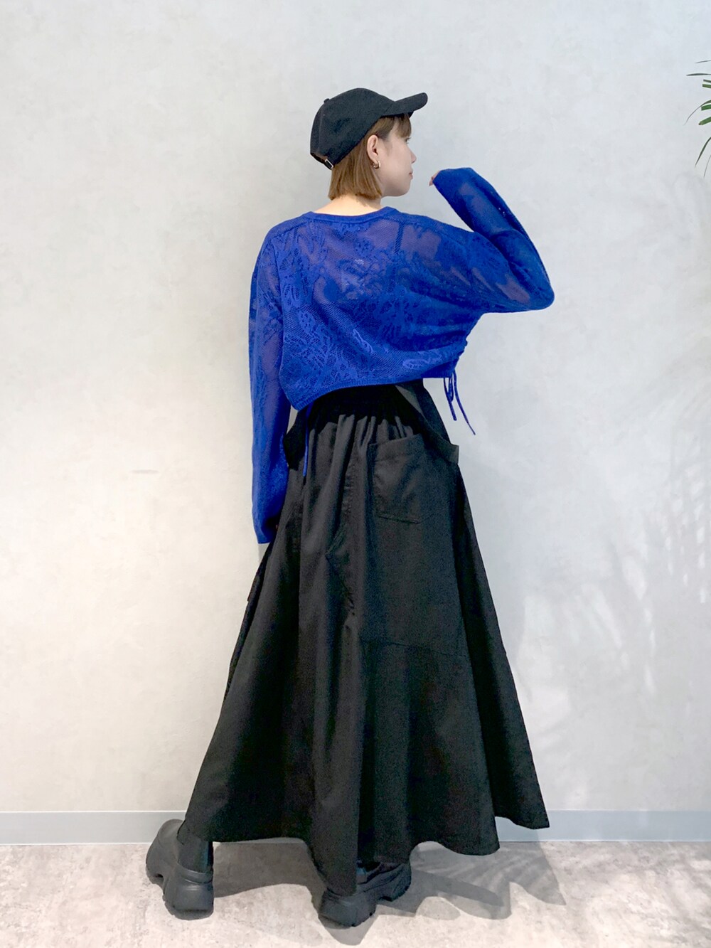 ブラック系のジャンパースカート、ブルー系のニット/セーター、ブラック系のブーツを着用したレディースの秋コーディネートの3枚目の写真