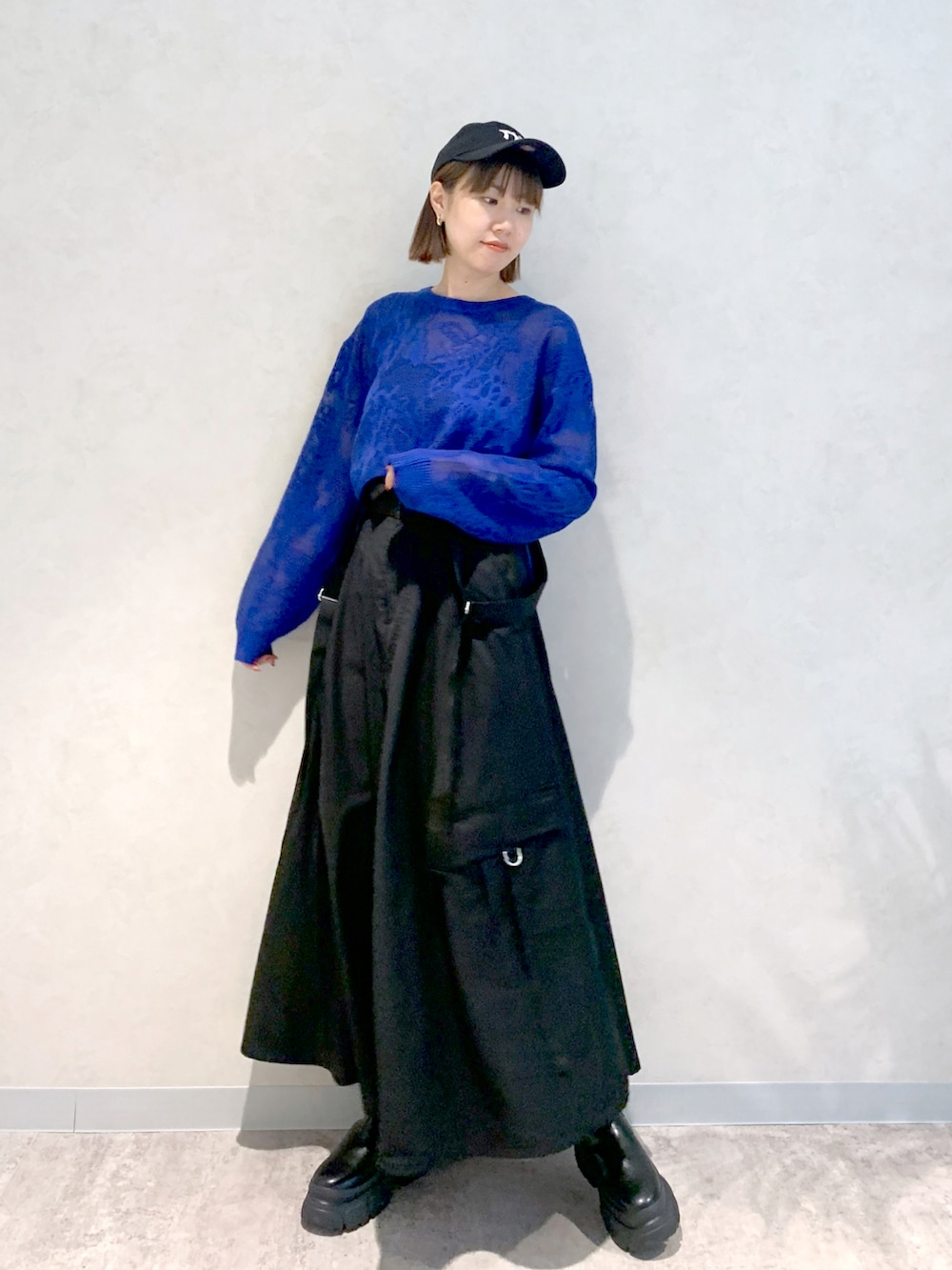 ブラック系のジャンパースカート、ブルー系のニット/セーター、ブラック系のブーツを着用したレディースの秋コーディネートの2枚目の写真