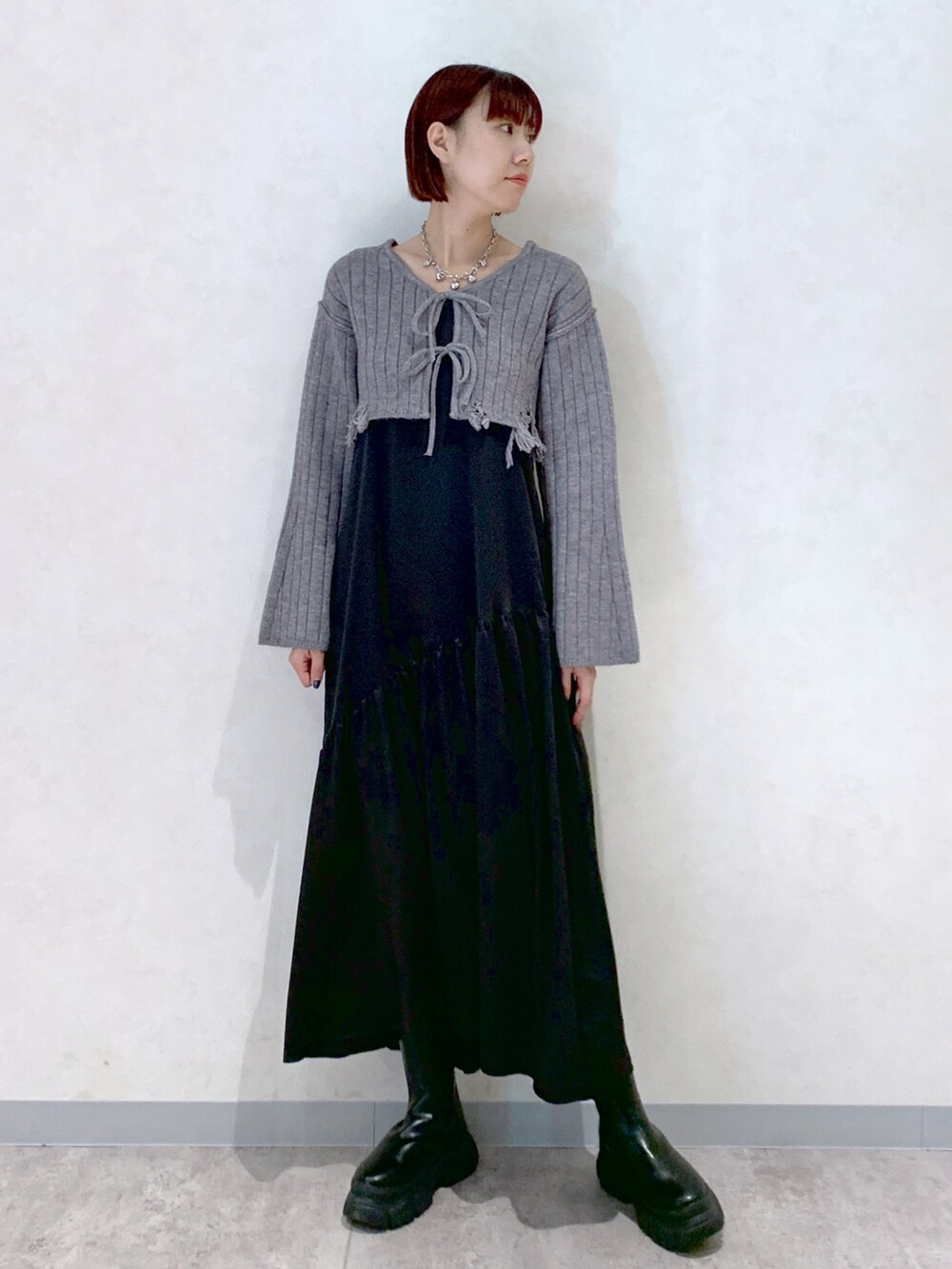 グレー系のワンピース、ブラック系のブーツを着用したレディースの秋コーディネートの2枚目の写真